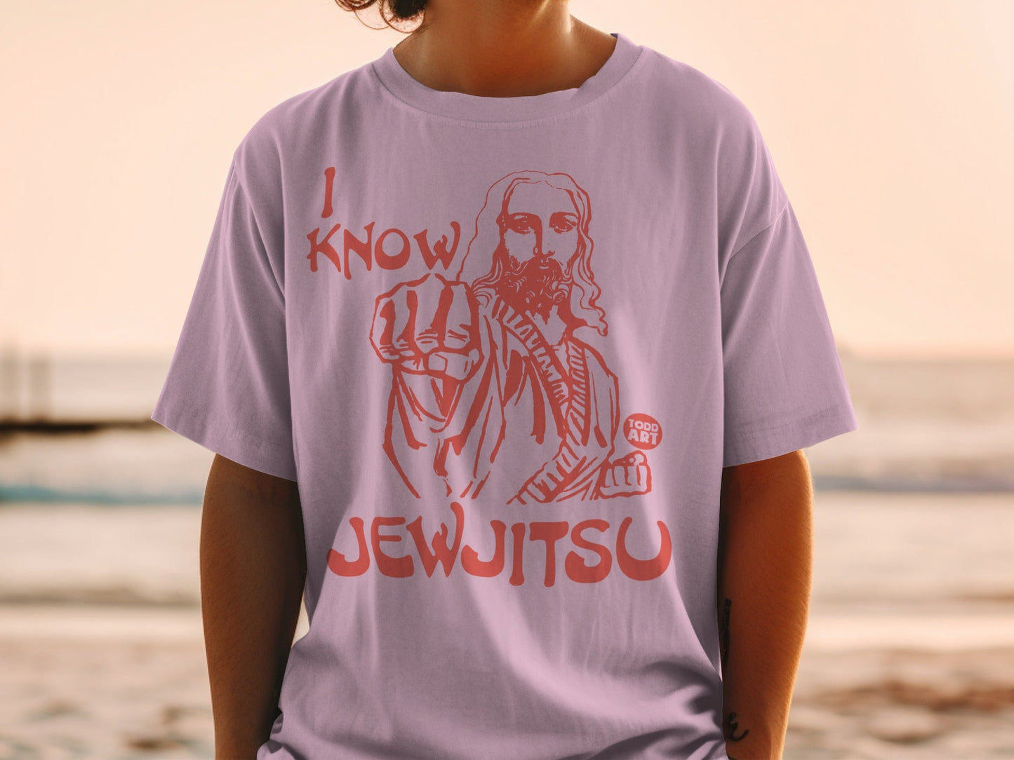 Pink t-shirt with graphic of Jesus pointing and text "I KNOW JEWJITSU".