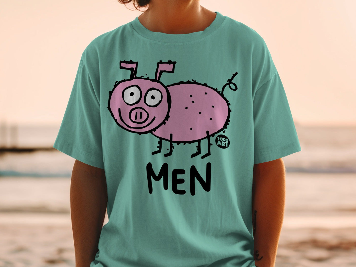 Teal t-shirt with a cartoon pink pig and the word "MEN" on it.
