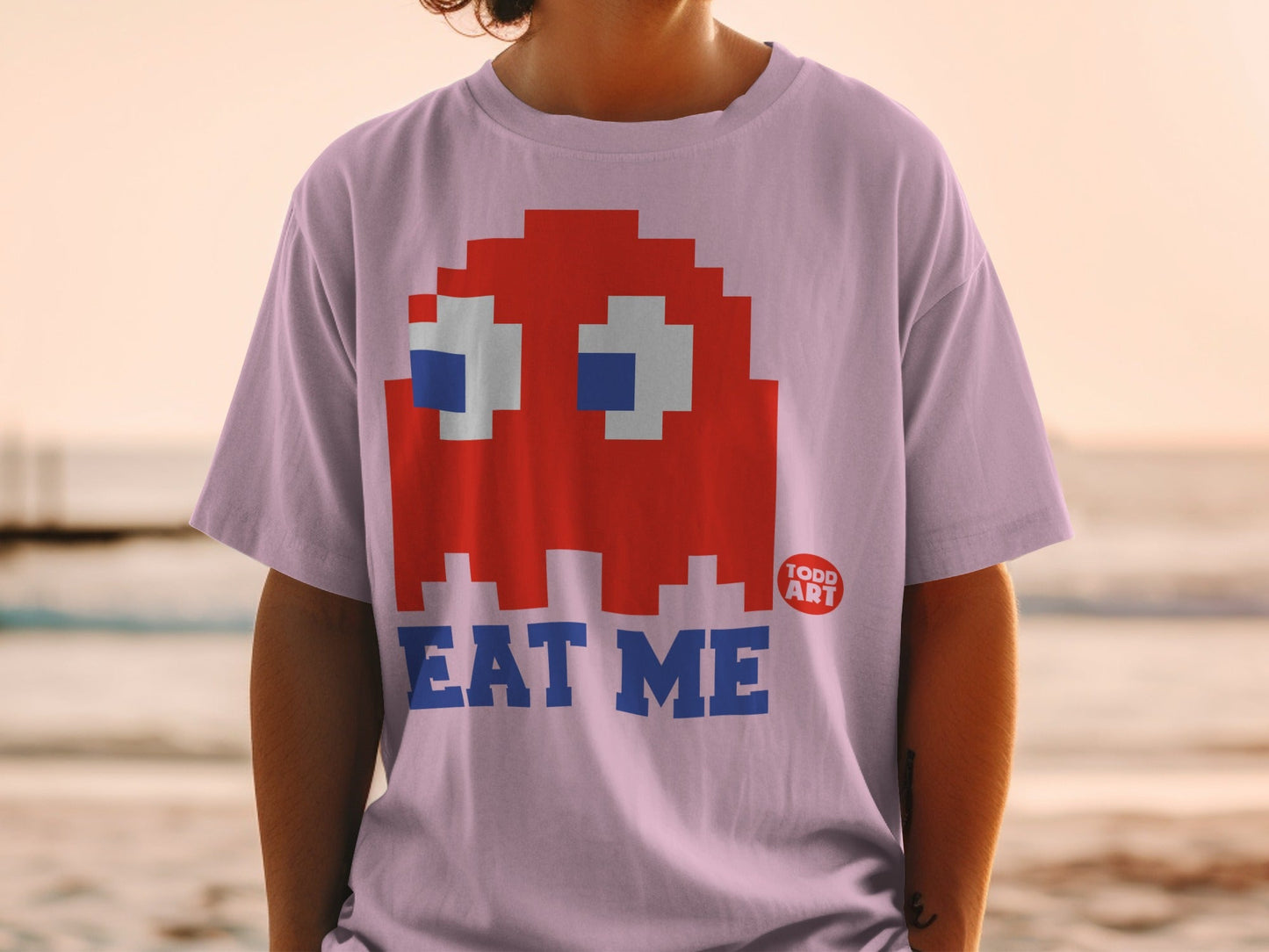 Pink t-shirt with red Pac-Man ghost and "EAT ME" text.