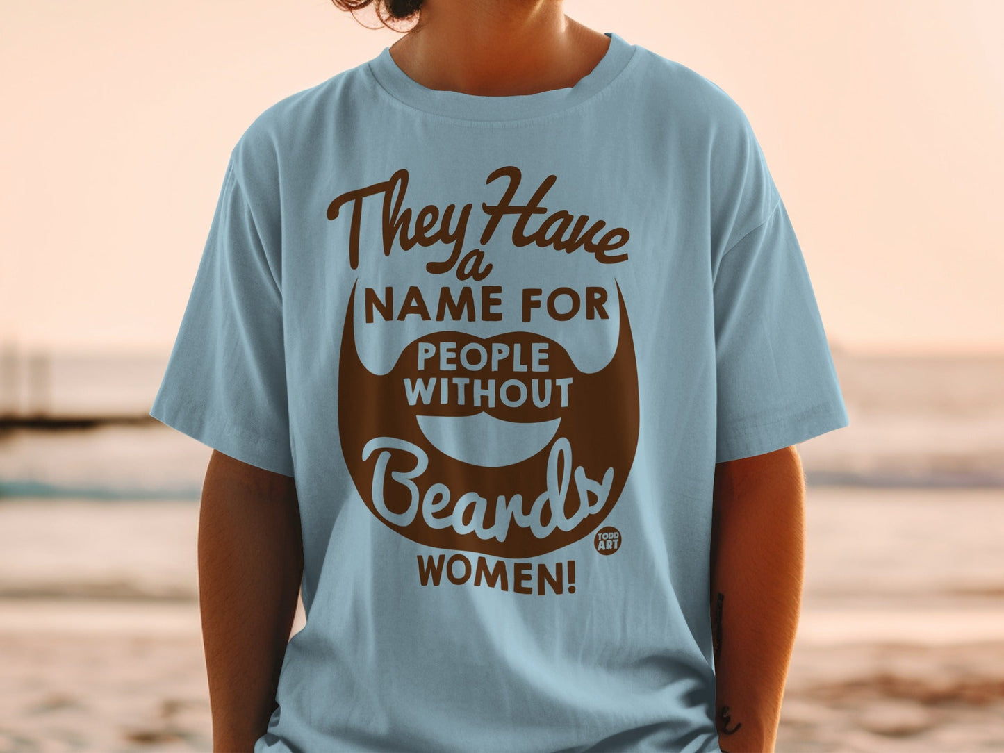 Light blue t-shirt with brown text and beard graphic: "They Have a Name For People Without Beards: WOMEN!"