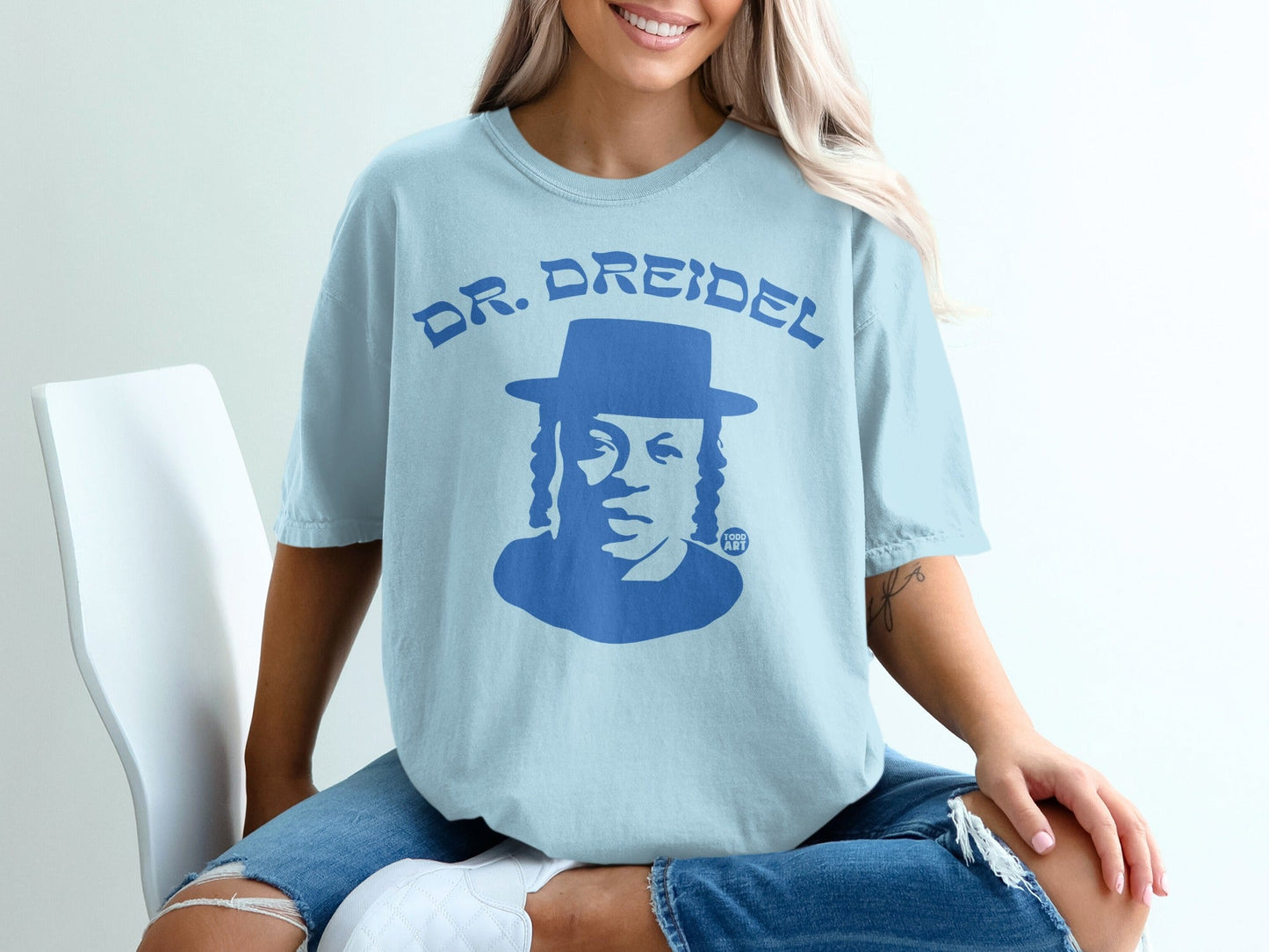 Light blue t-shirt with a blue portrait of a man wearing a hat, text "DR. DREIDEL".