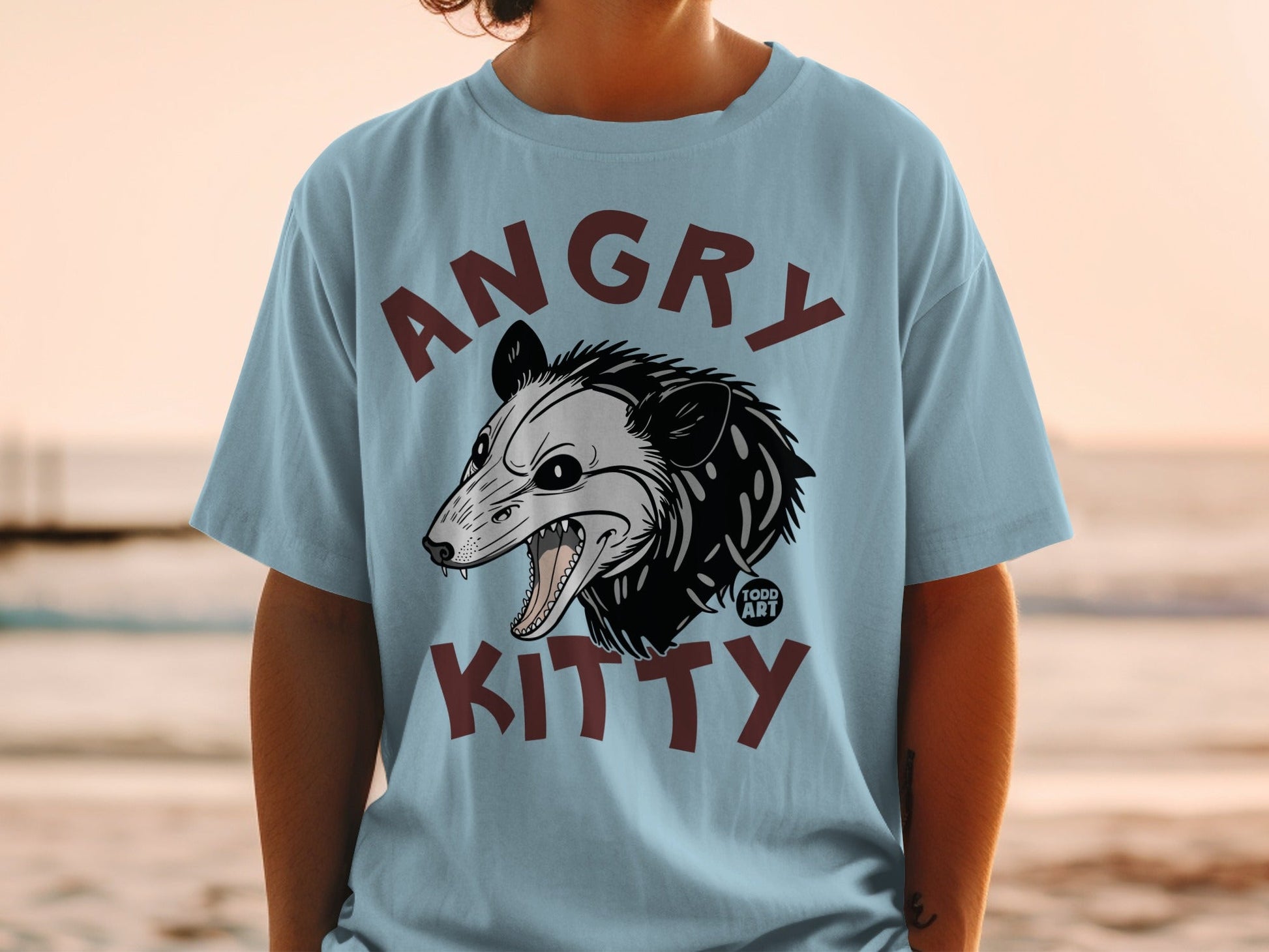 Light blue t-shirt with "ANGRY KITTY" and a stylized possum head.