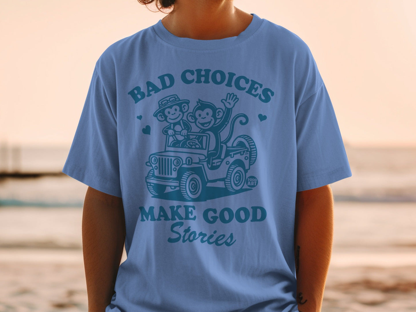 Blue t-shirt with cartoon monkeys in a jeep, "BAD CHOICES MAKE GOOD STORIES."