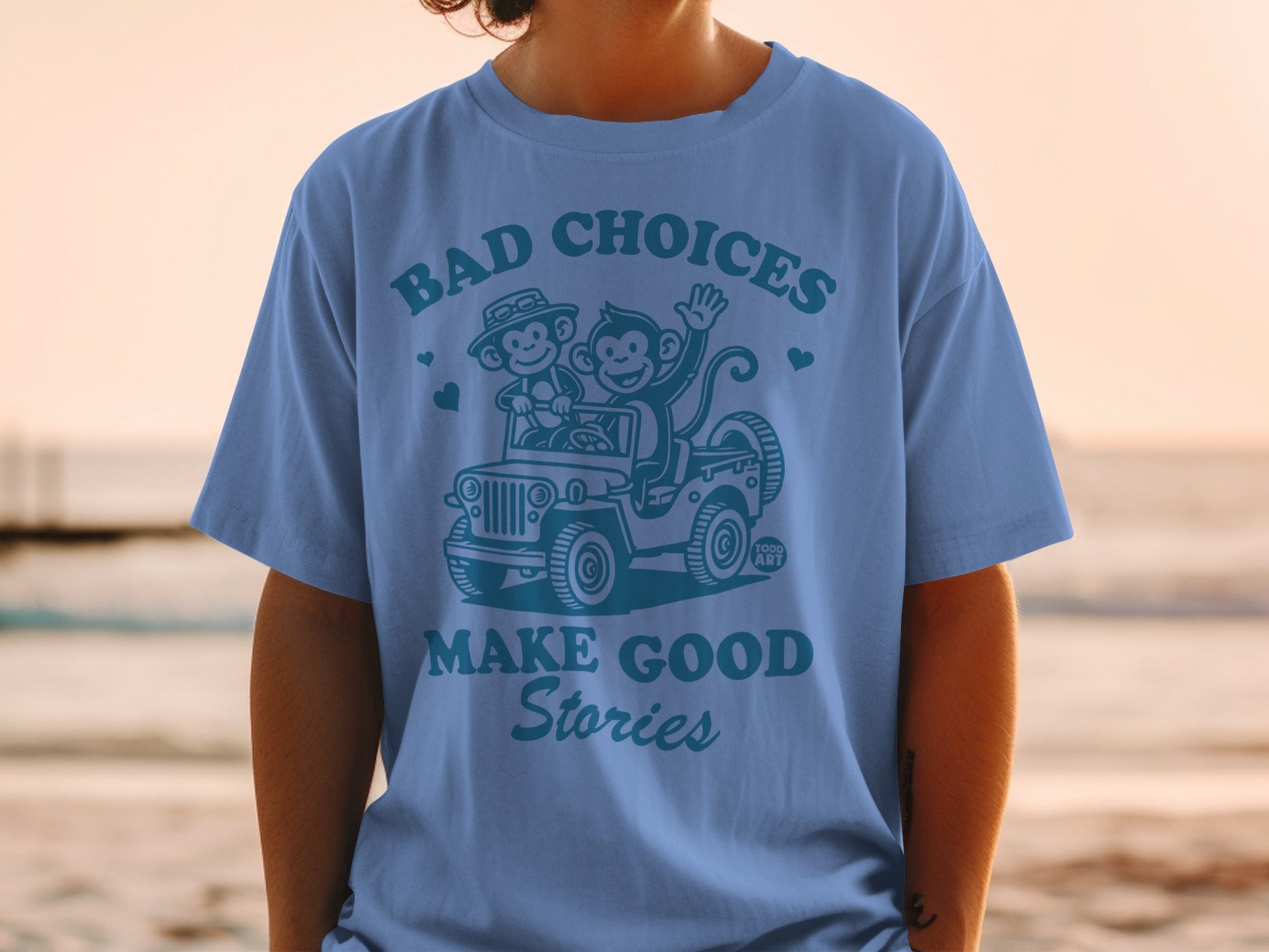 Blue t-shirt with cartoon monkeys in a jeep, "BAD CHOICES MAKE GOOD STORIES."
