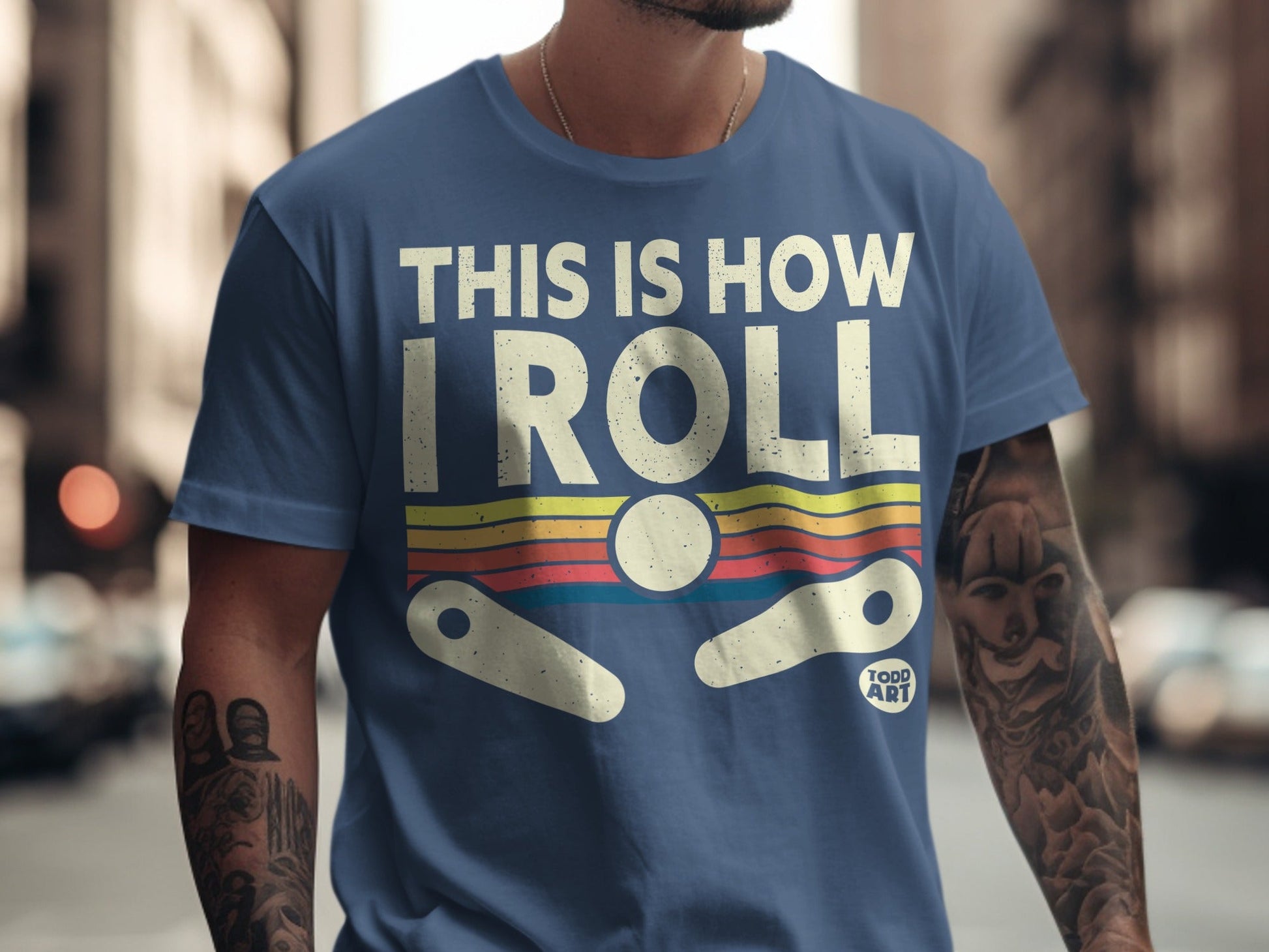 Blue t-shirt with "THIS IS HOW I ROLL" text and pinball graphic.