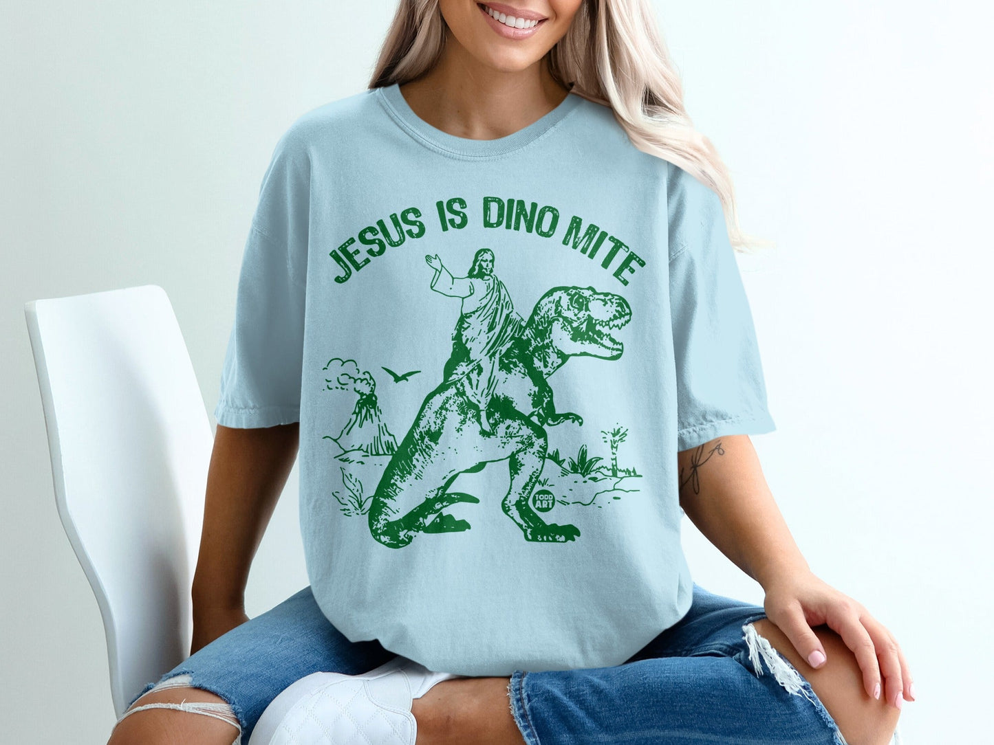 Jesus is Dino Mite graphic on a light blue t-shirt.