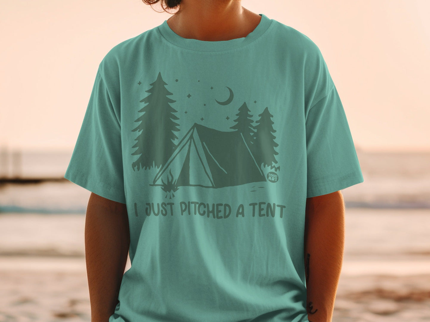Teal t-shirt with a graphic of a tent, trees, and moon, reading "I just pitched a tent."