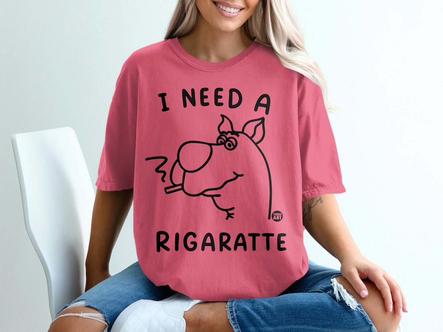 Pink t-shirt with cartoon dog smoking a cigarette and text "I NEED A RIGARETTE".