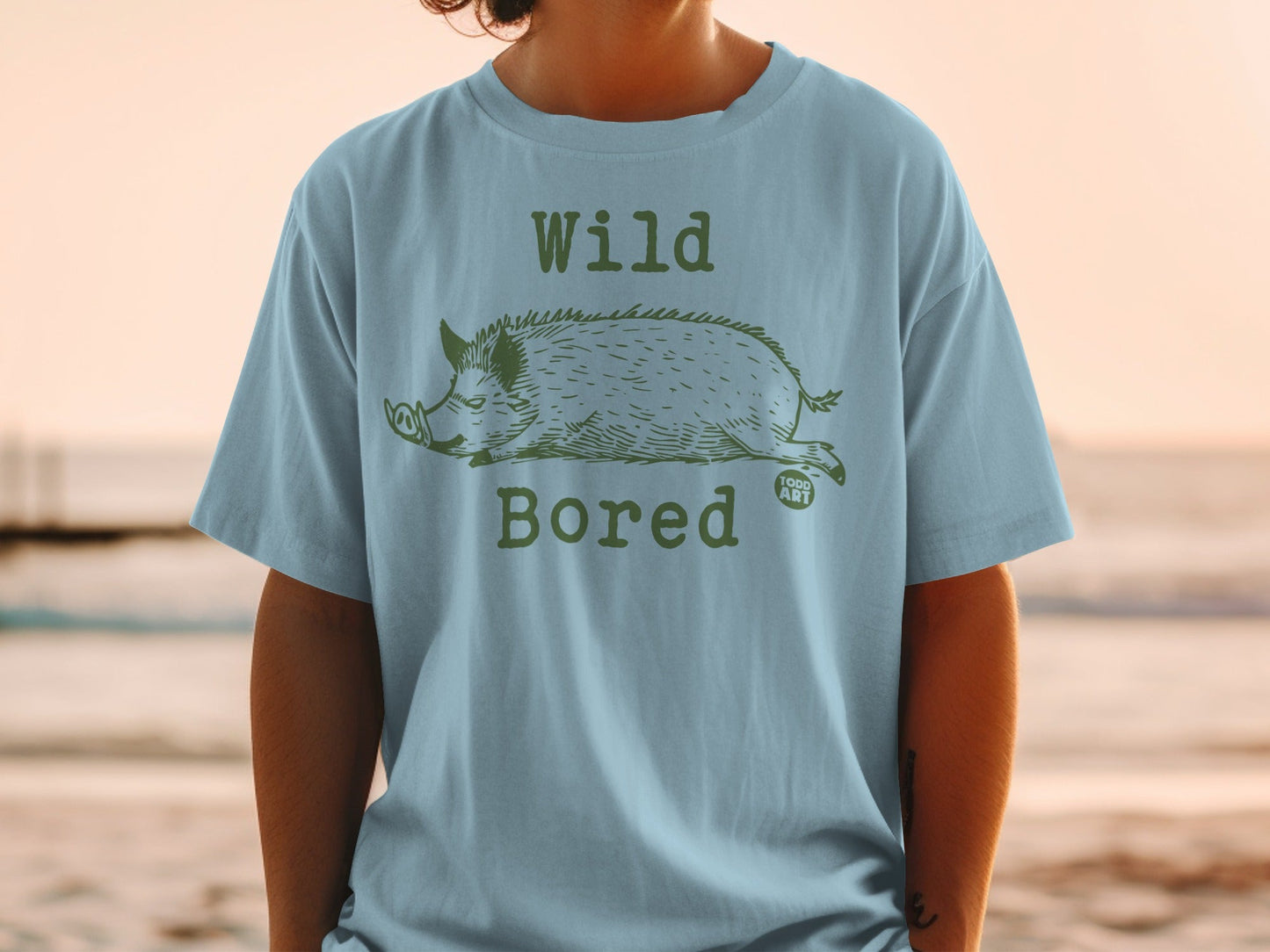 Light blue t-shirt with a green graphic of a wild boar and "Wild Bored" text.