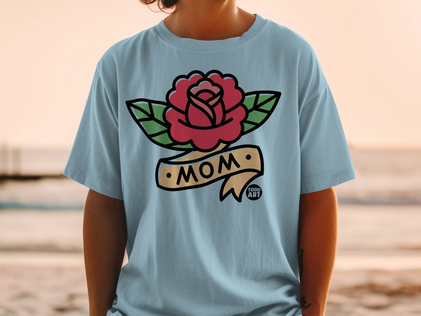 Light blue t-shirt with tattoo-style rose and "MOM" banner.