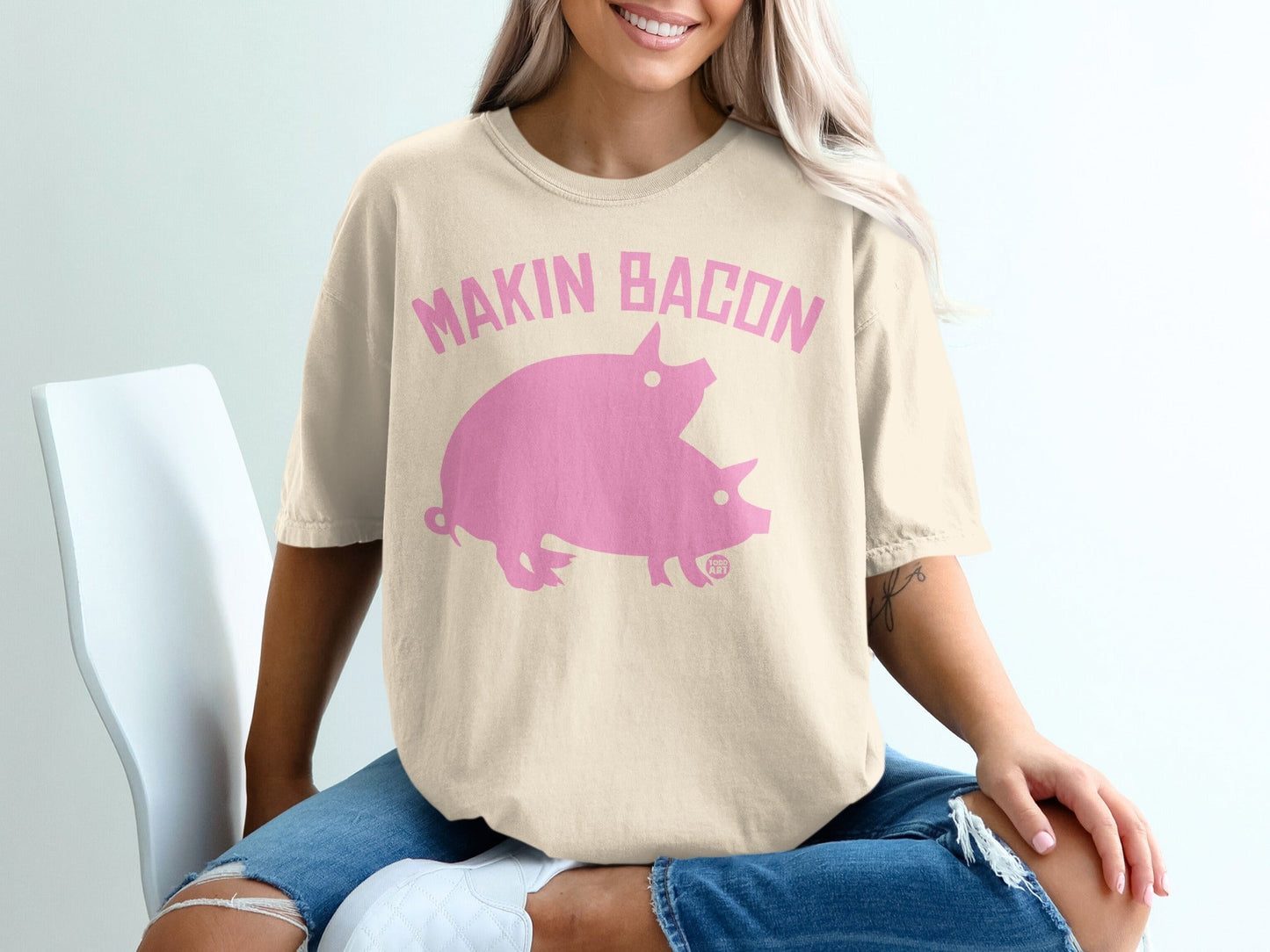 Cream t-shirt with pink "Makin Bacon" text and two pink pigs graphic.
