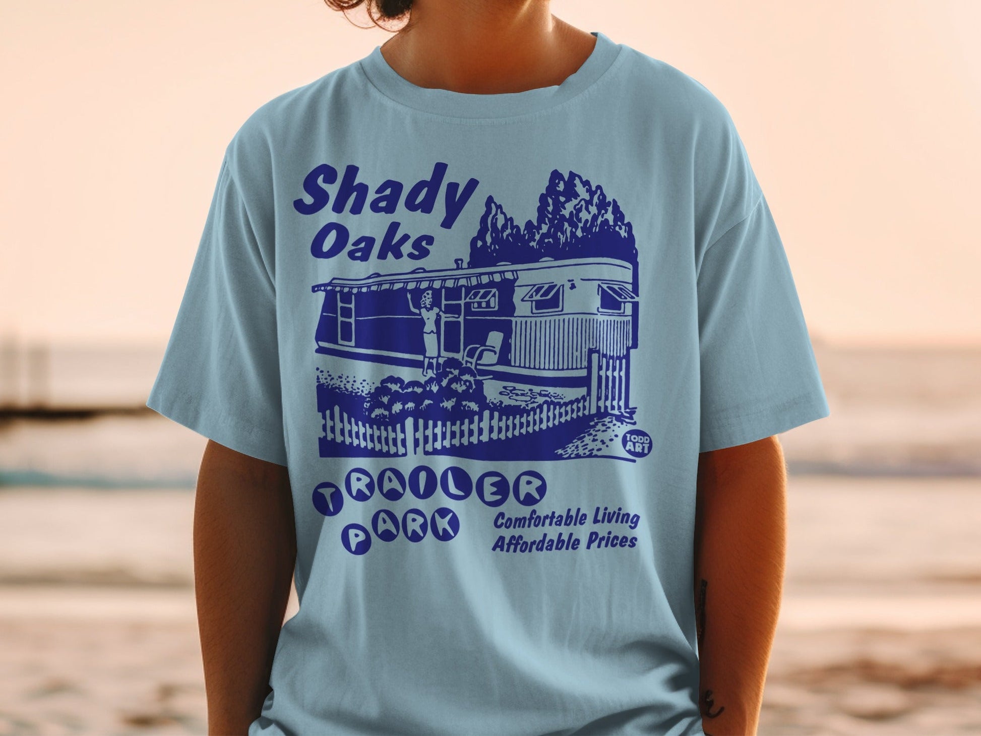Blue t-shirt with "Shady Oaks Trailer Park" graphic and text.
