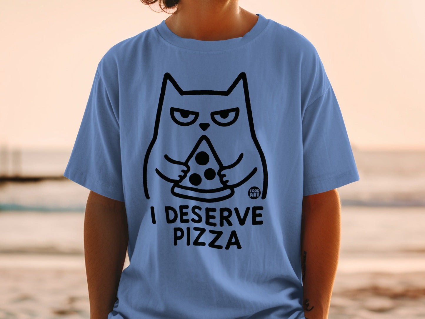 Blue t-shirt with a black outline drawing of a cat holding a slice of pizza and the text "I DESERVE PIZZA".
