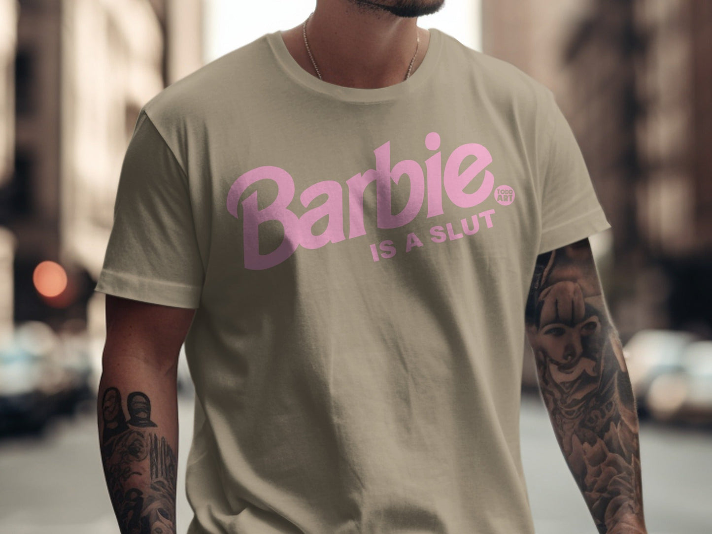 Tan t-shirt with pink "Barbie IS A SLUT" text and a tattoo on the model's arm.