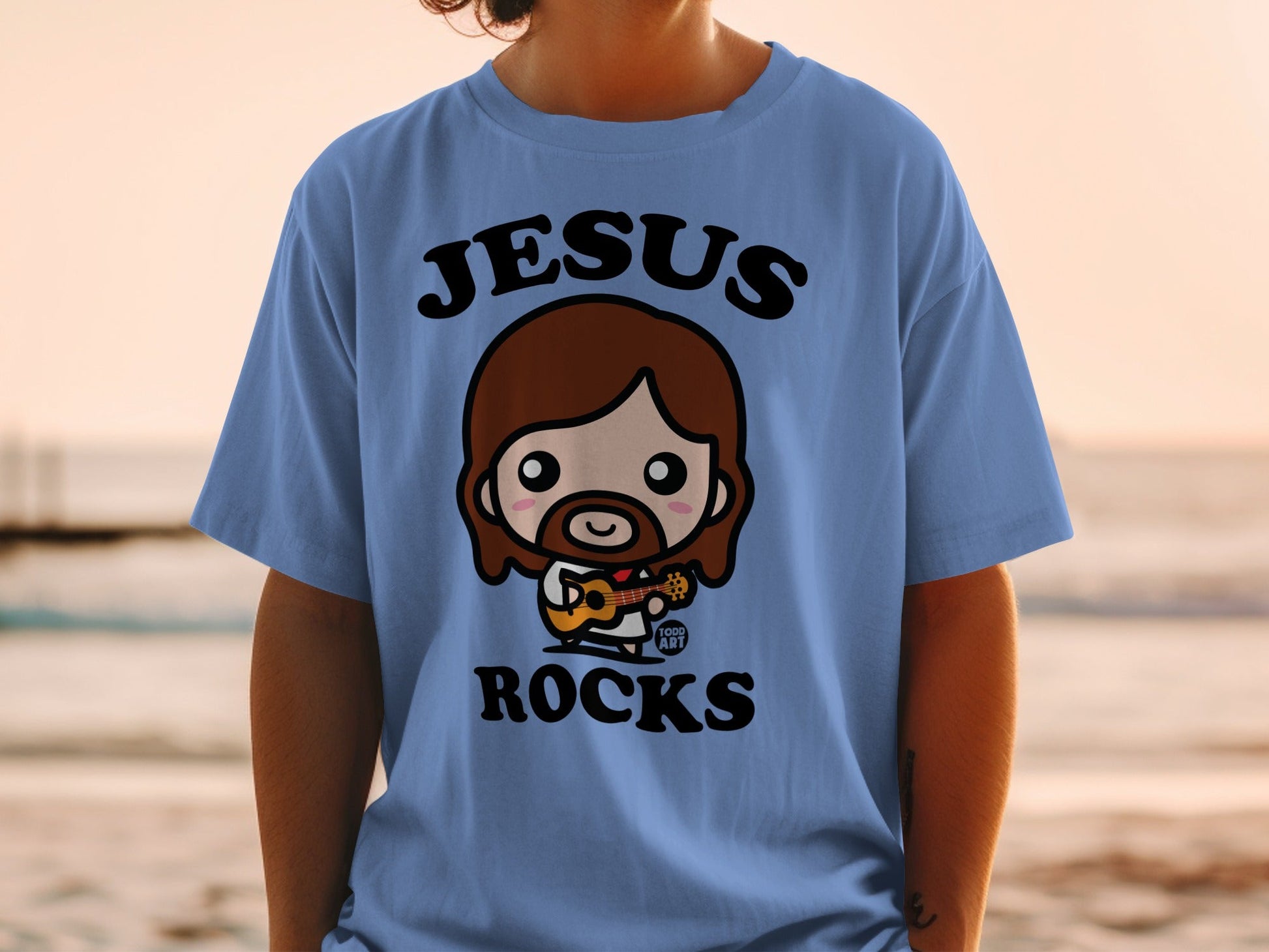 Blue t-shirt with cartoon Jesus playing guitar, text "JESUS ROCKS".