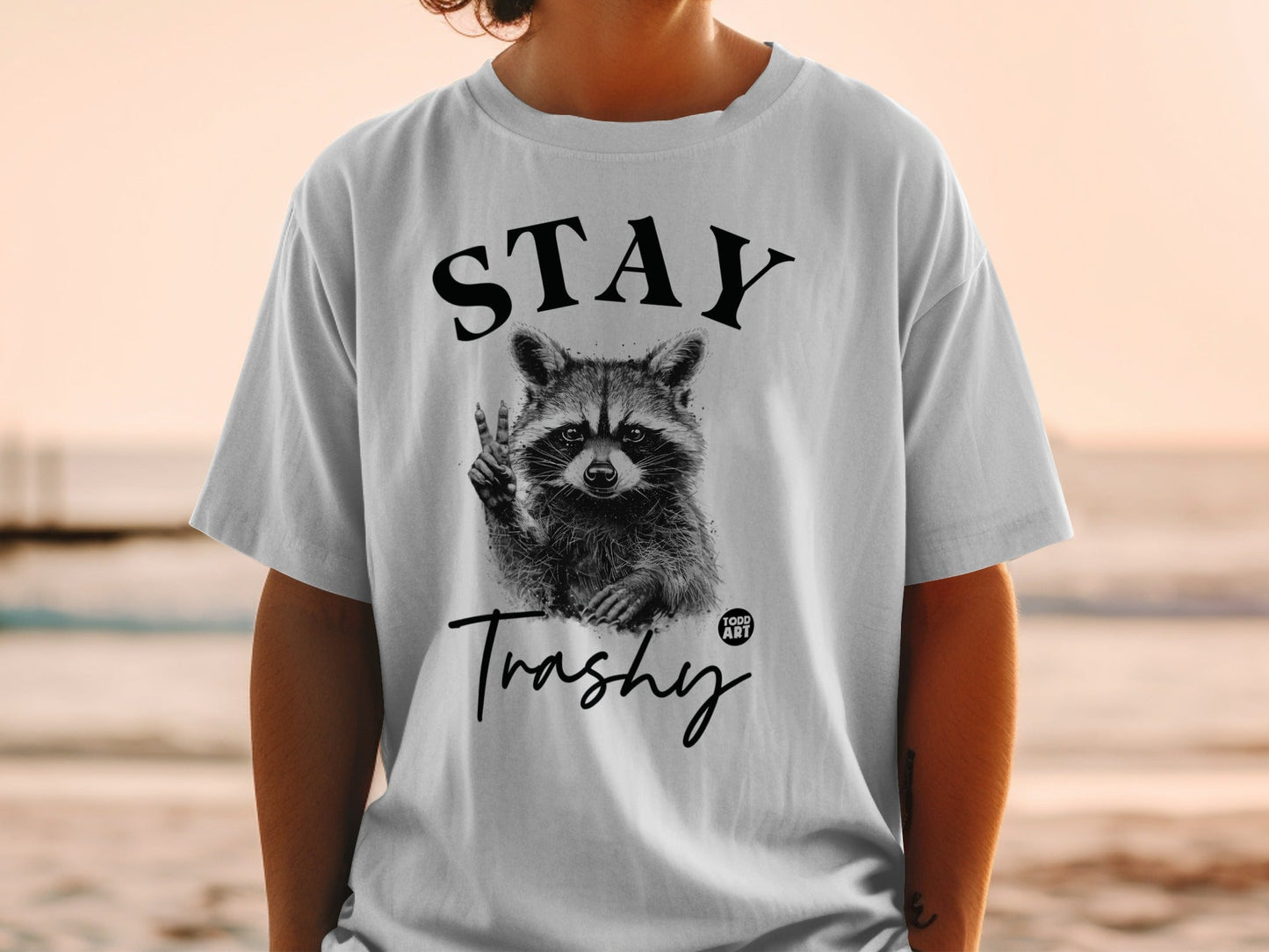 T-shirt with raccoon giving peace sign and "STAY Trashy" text.