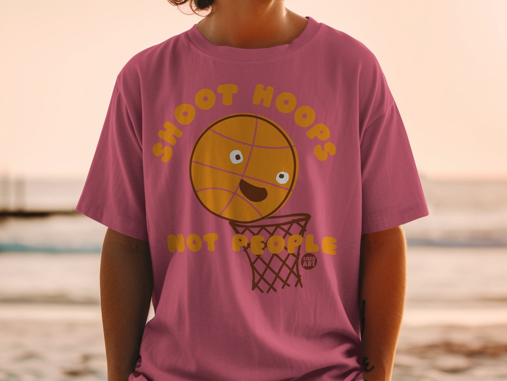 Pink t-shirt with cartoon basketball going into a net.