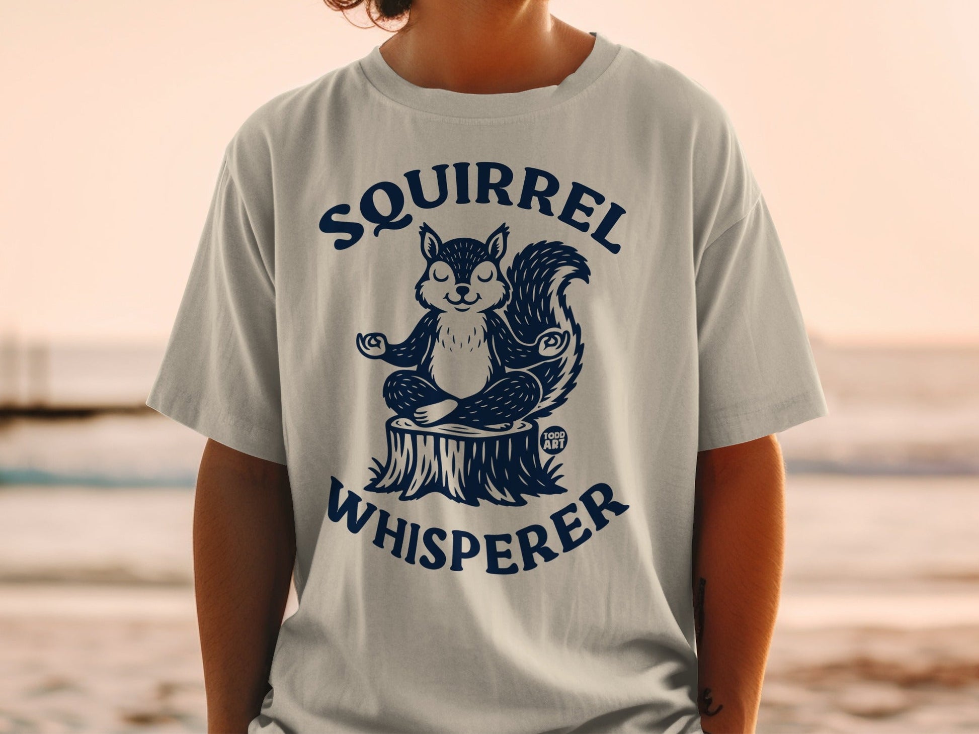 T-shirt with a meditating squirrel on a log, "Squirrel Whisperer" text.
