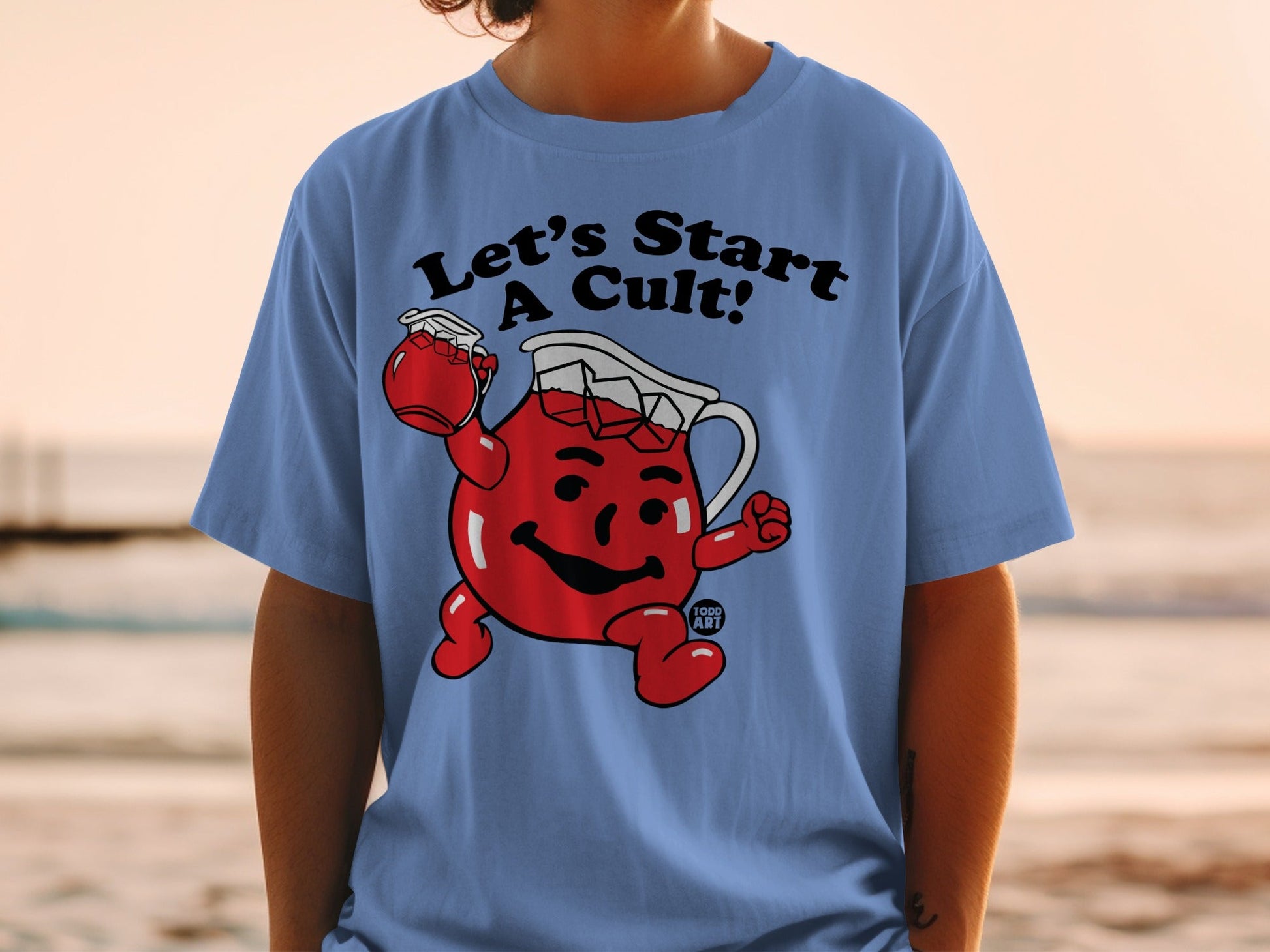 Light blue t-shirt with cartoon character holding a jar, text "Let's Start A Cult!".
