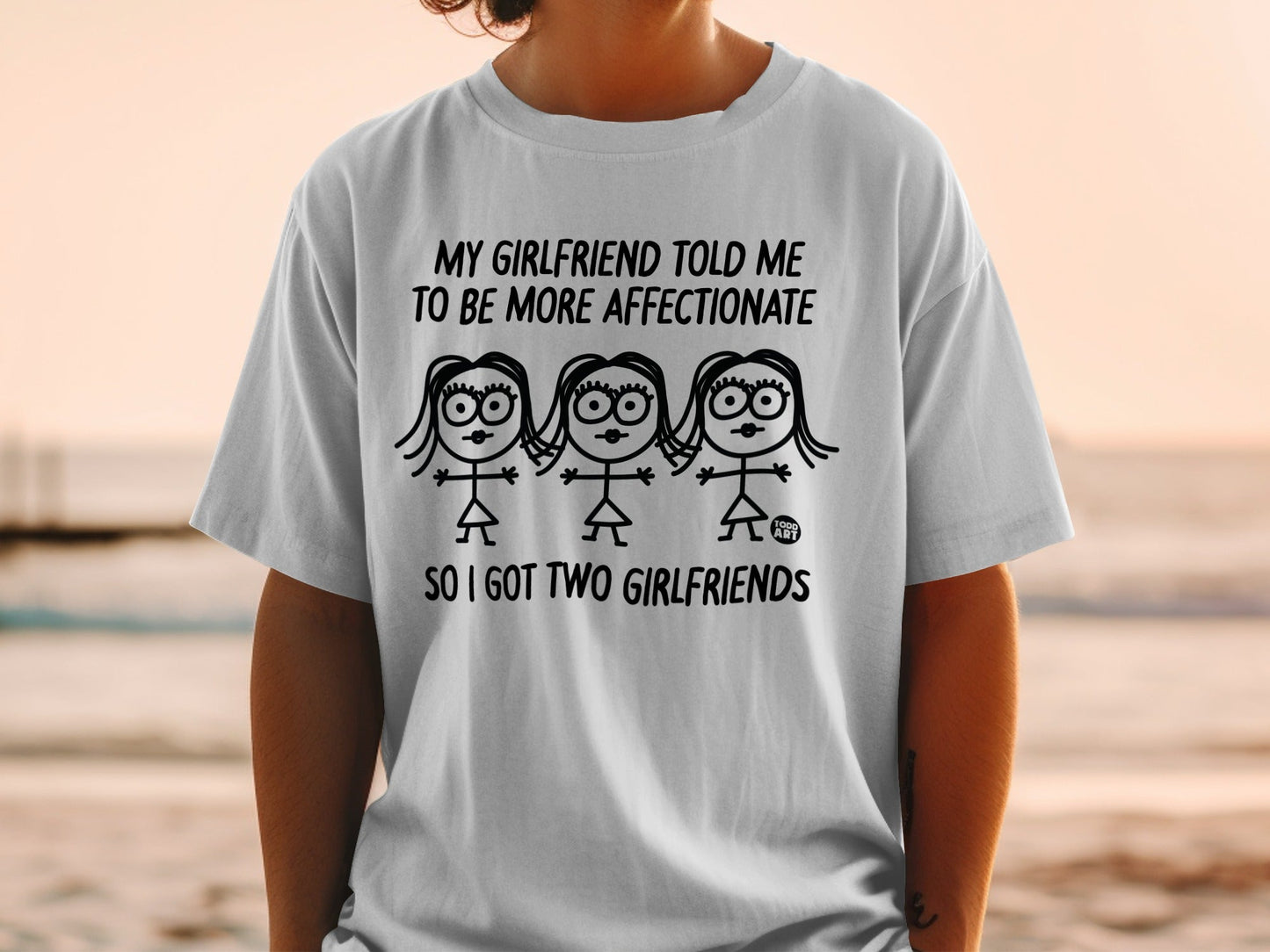 T-shirt with cartoon drawing and text: "My girlfriend told me to be more affectionate so I got two girlfriends."