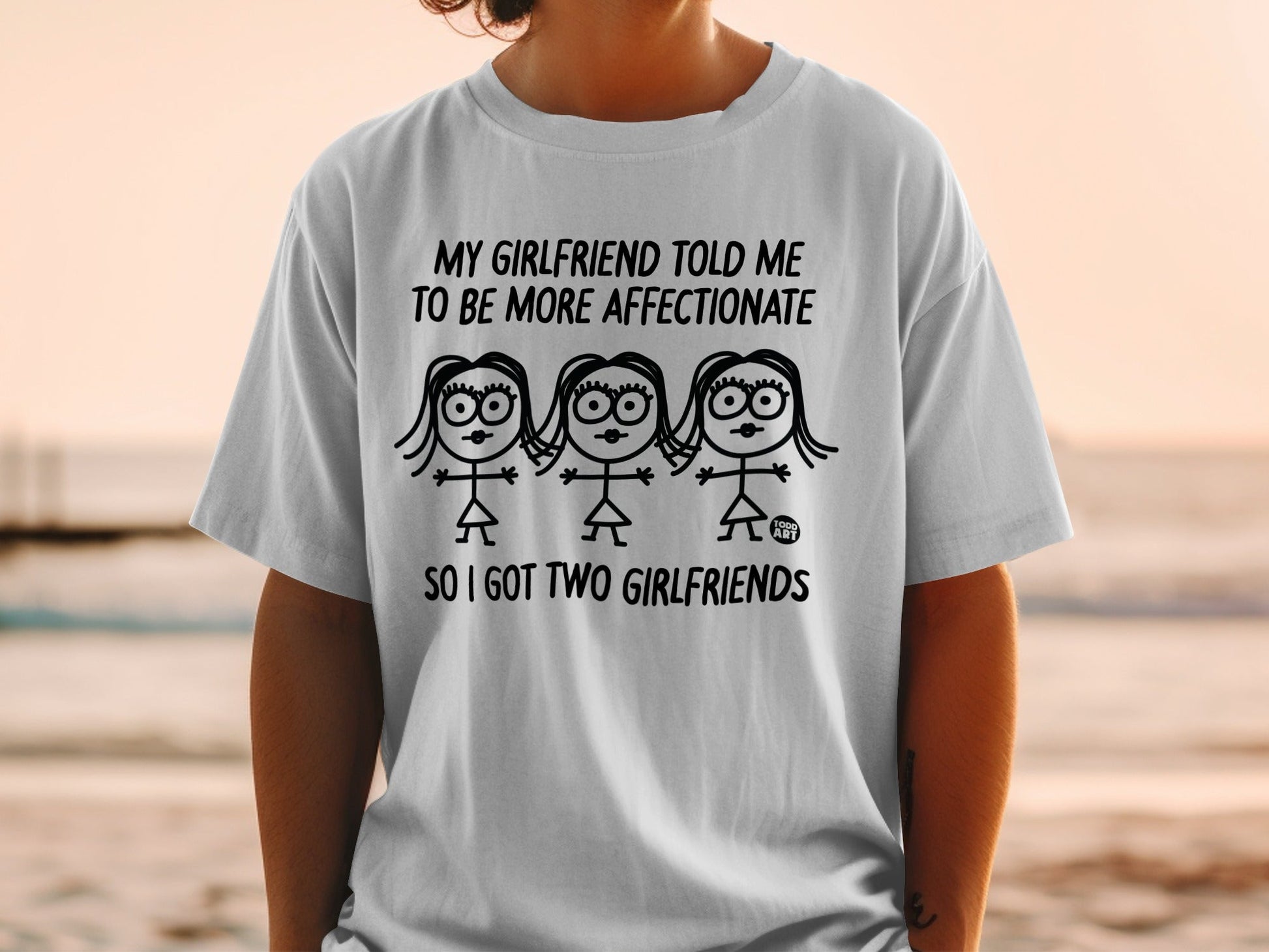 T-shirt with cartoon drawing and text: "My girlfriend told me to be more affectionate so I got two girlfriends."