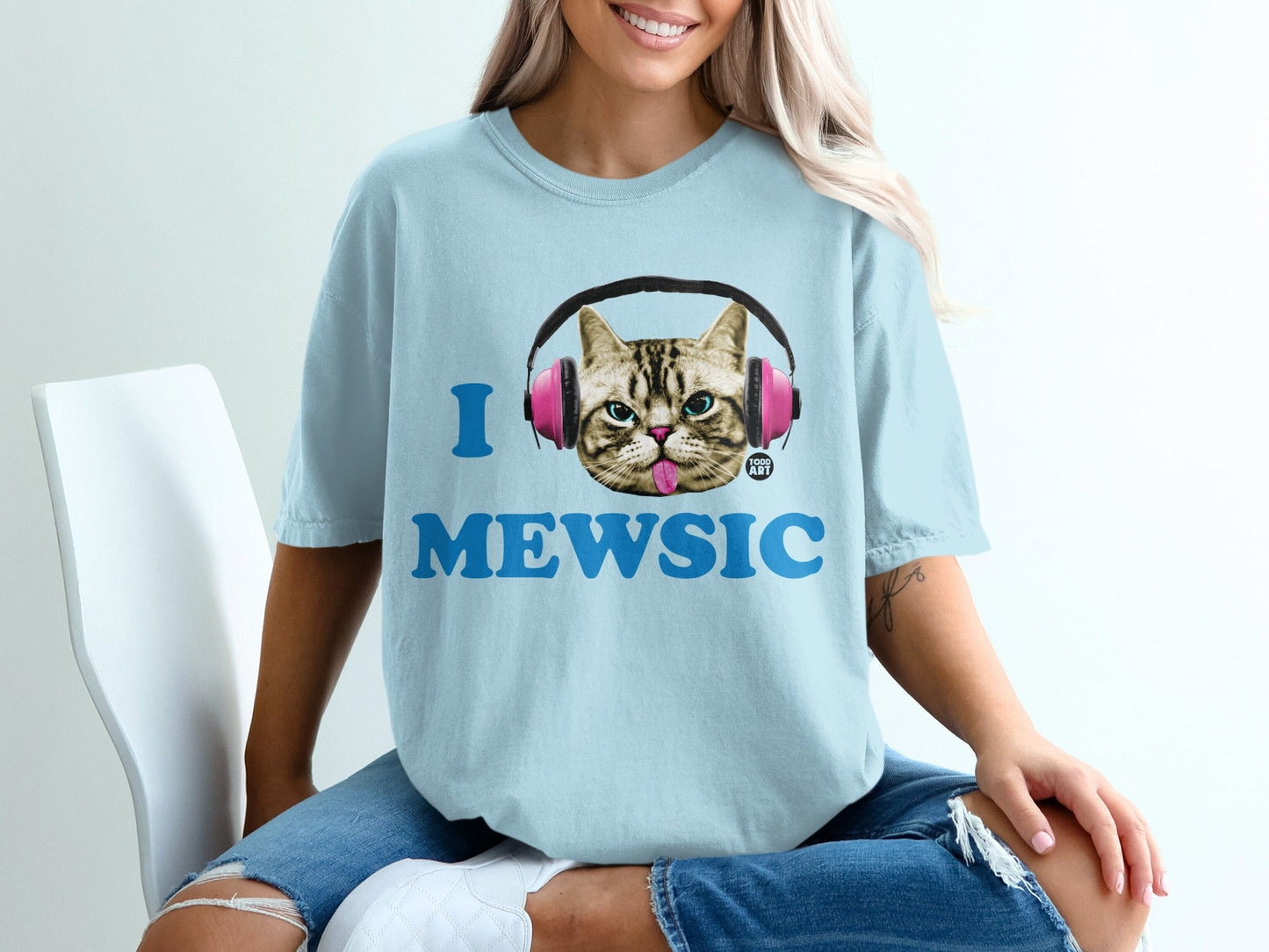 Light blue t-shirt with "I MEWSIC" text and pink headphones on a cat graphic.