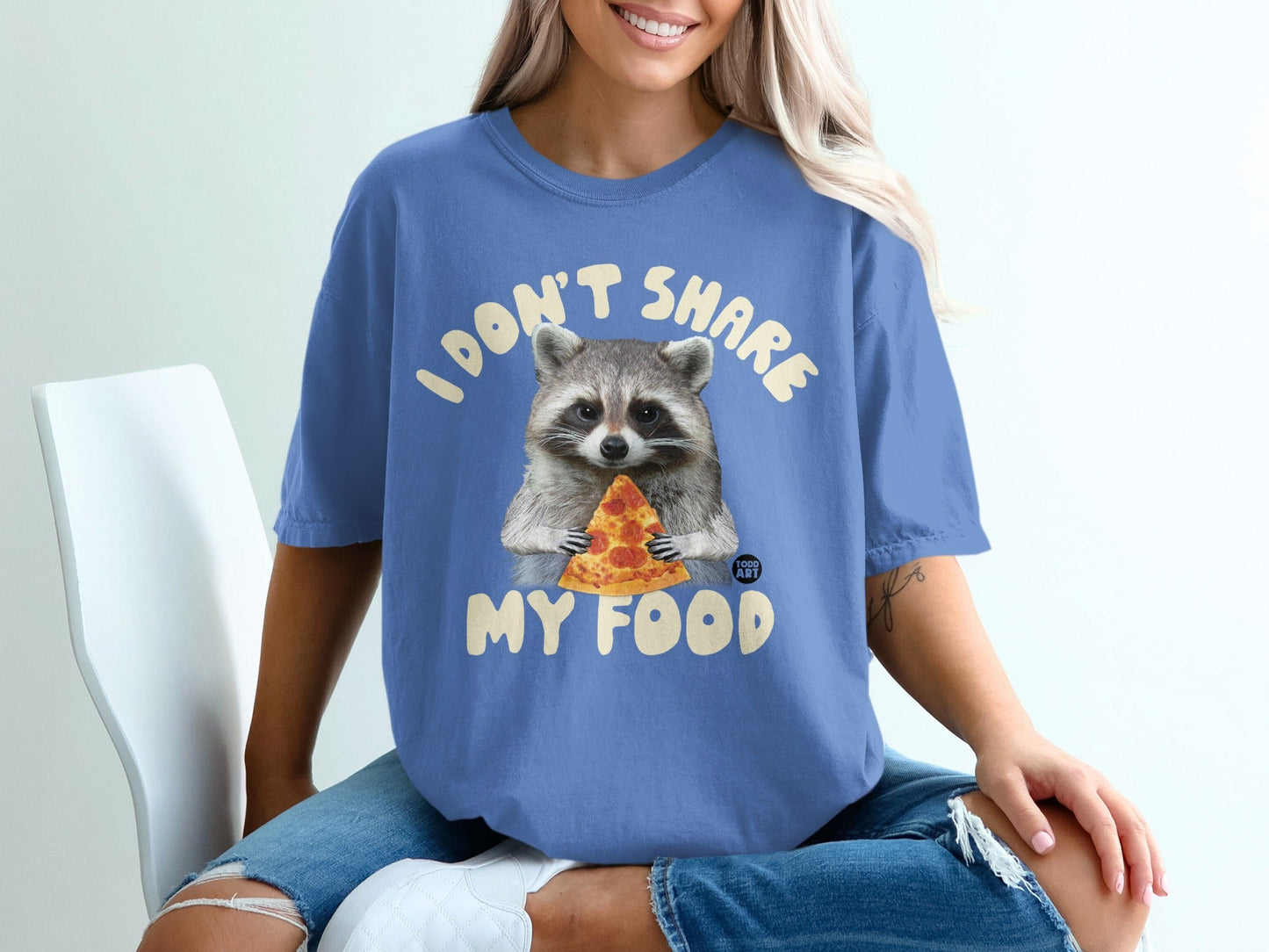 Raccoon wearing t-shirt with "I DON'T SHARE MY FOOD" text and holding pizza.