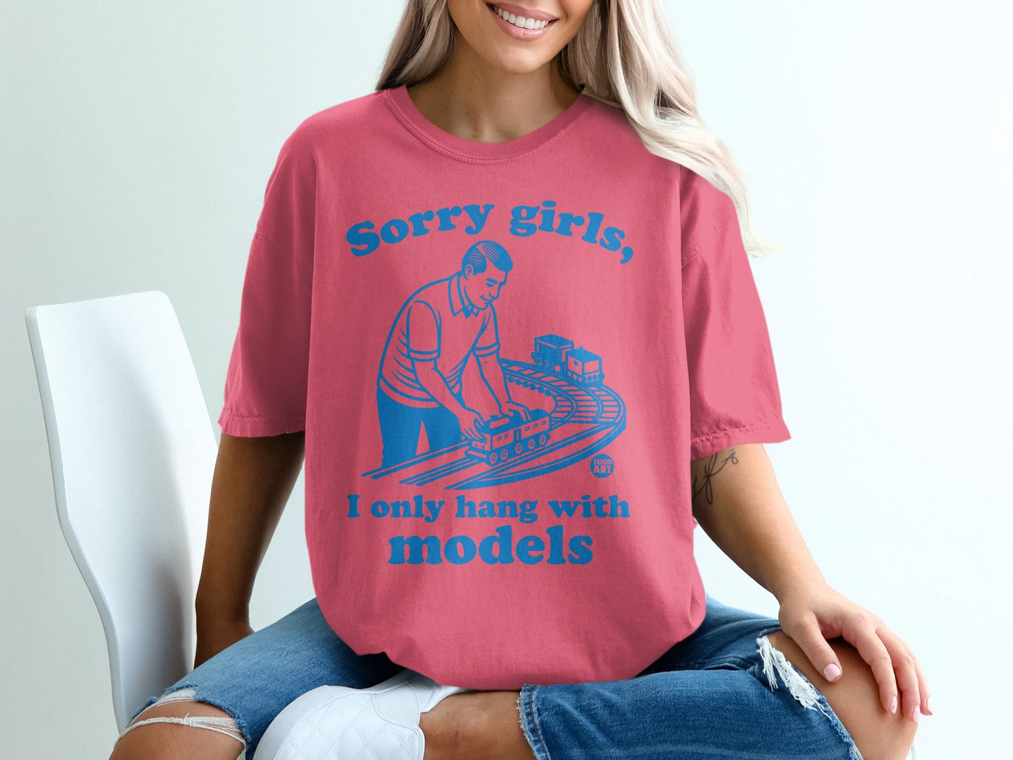 Pink t-shirt with blue text: "Sorry girls, I only hang with models" and graphic of a man with a toy train.