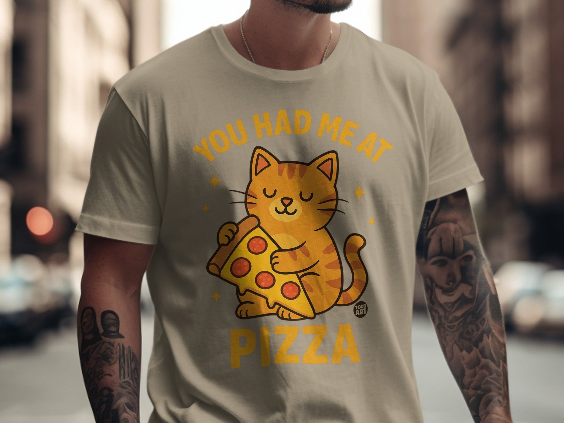 Orange tabby cat wearing a t-shirt that says "You Had Me At Pizza."