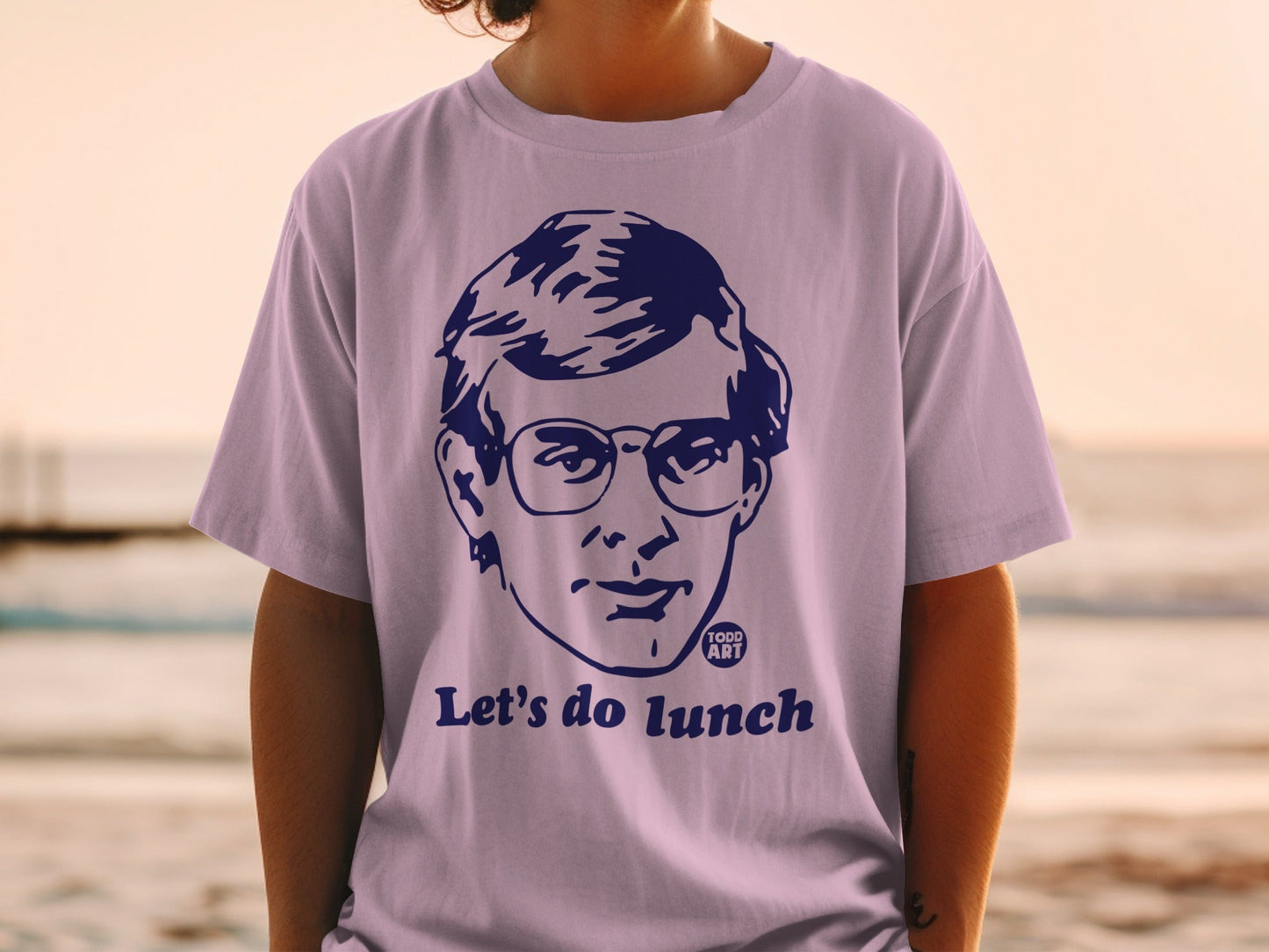 Purple t-shirt with a blue graphic of a man in glasses and "Let's do lunch."