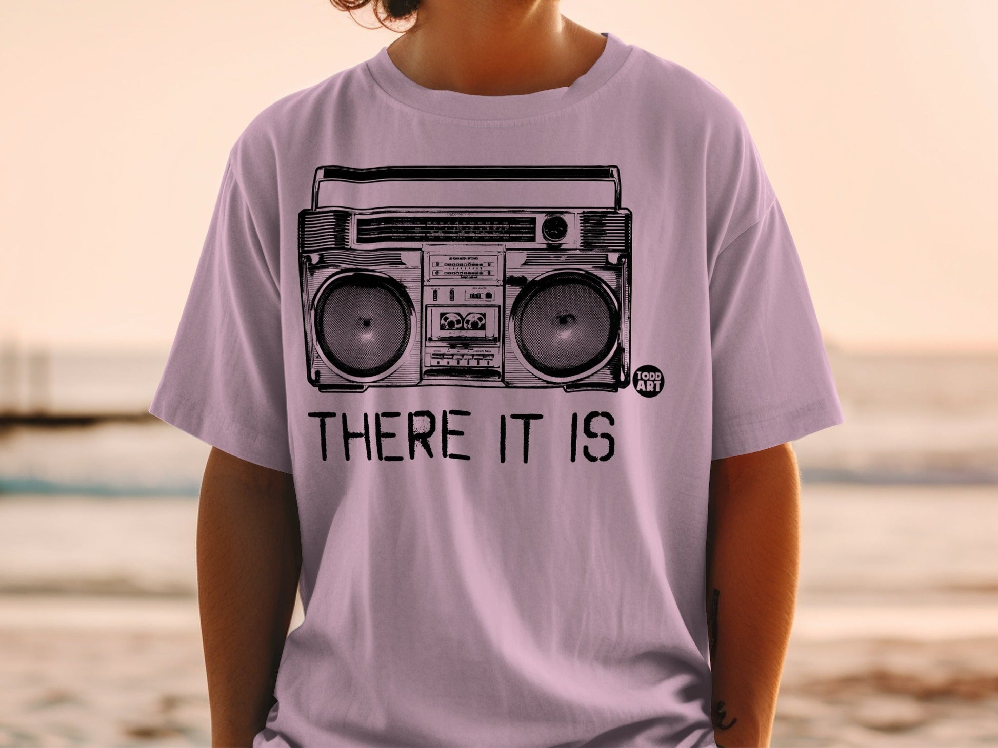 Purple t-shirt with a black graphic of a boombox and text "THERE IT IS".
