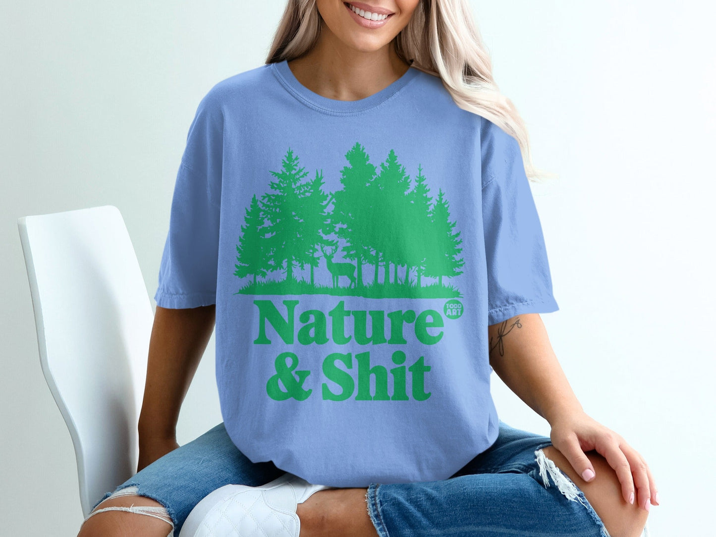 Light blue t-shirt with green pine trees and text "Nature & Shit".