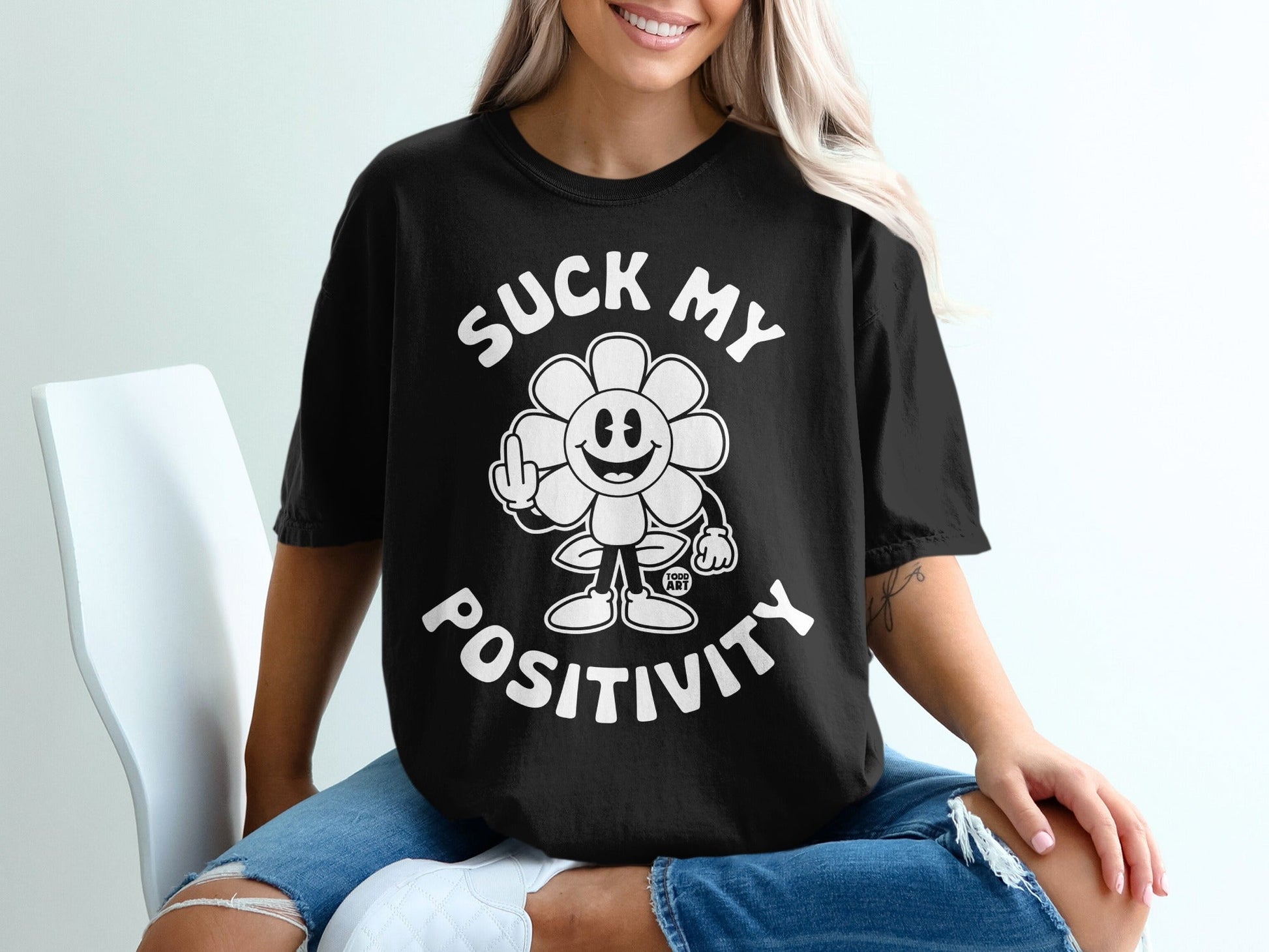 Black t-shirt with a cartoon flower flipping off and text that reads "SUCK MY POSITIVITY".