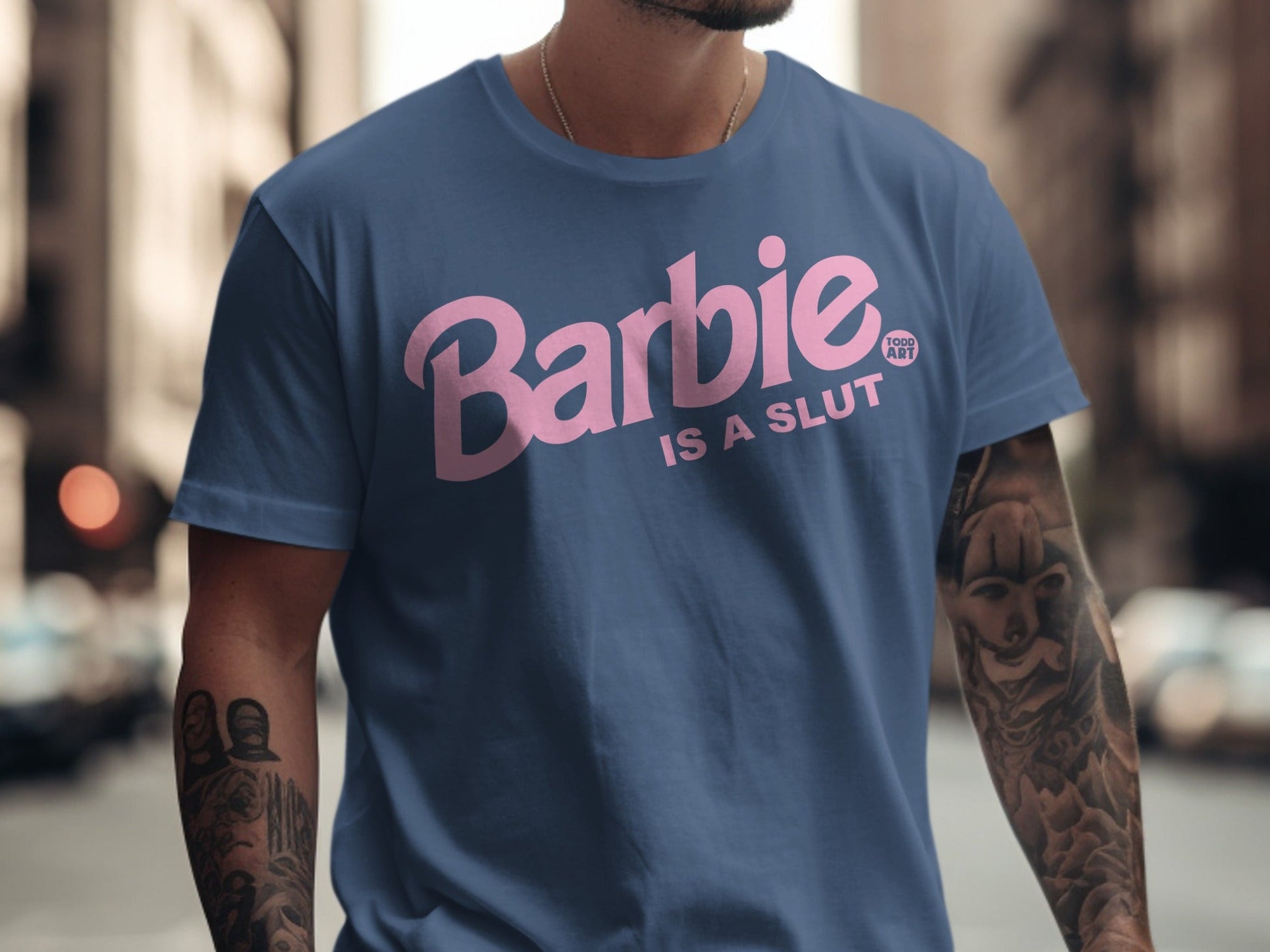 Blue t-shirt with pink "Barbie IS A SLUT" text and tattoo on arm.