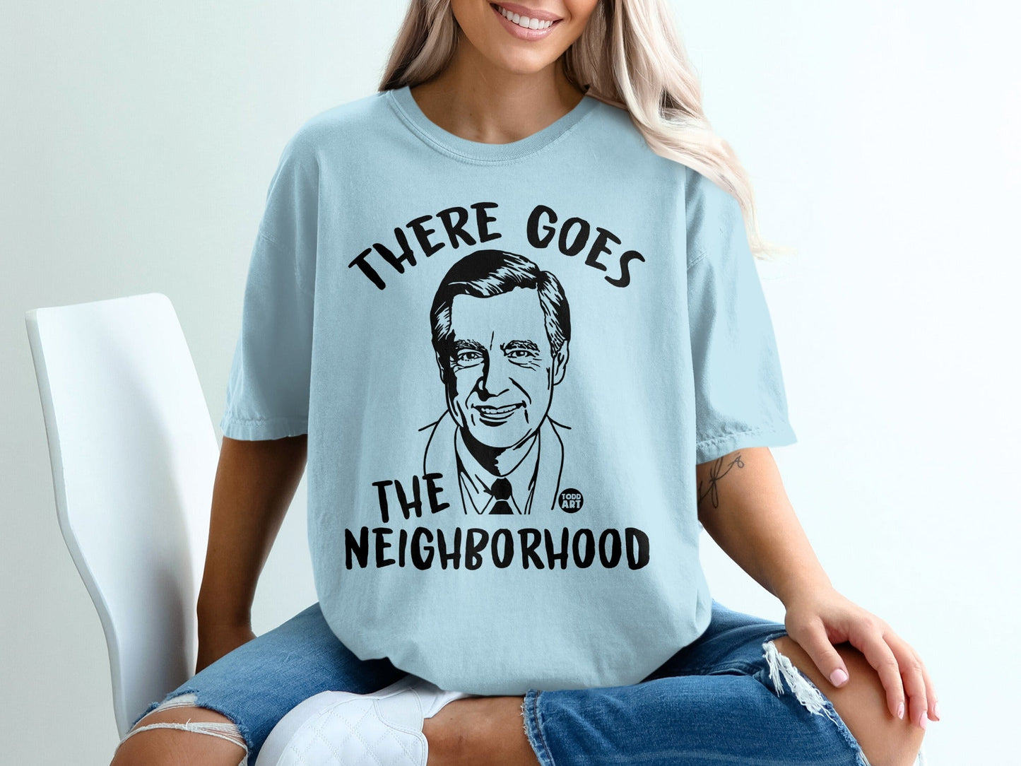 Light blue t-shirt featuring a drawing of Fred Rogers with "THERE GOES THE NEIGHBORHOOD" text.