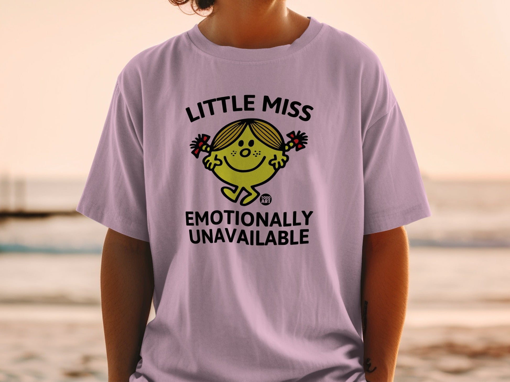 Light purple t-shirt with "Little Miss Emotionally Unavailable" text and character.