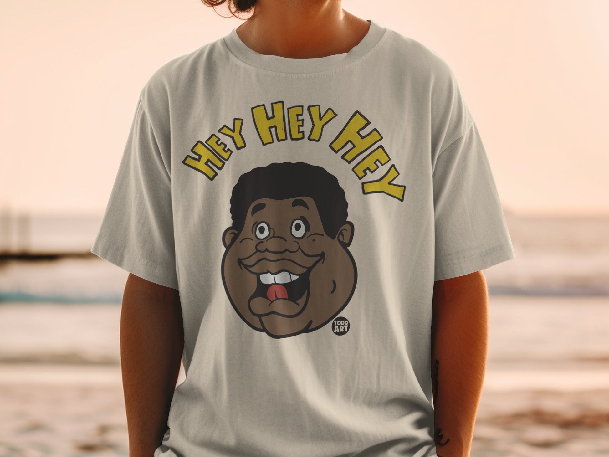 T-shirt with cartoon man saying "HEY HEY HEY" and "1000 ART" logo.
