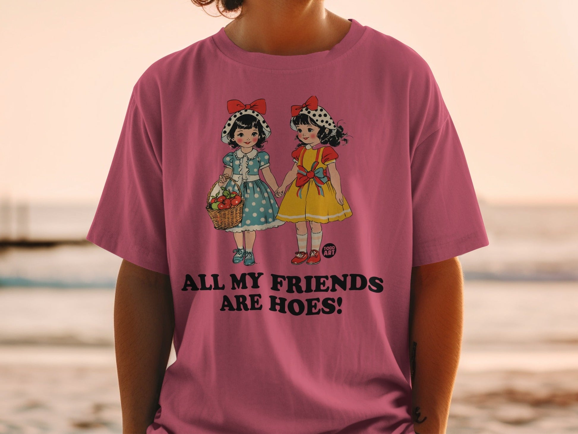 Pink t-shirt with illustration of two girls holding hands and text "ALL MY FRIENDS ARE HOES".