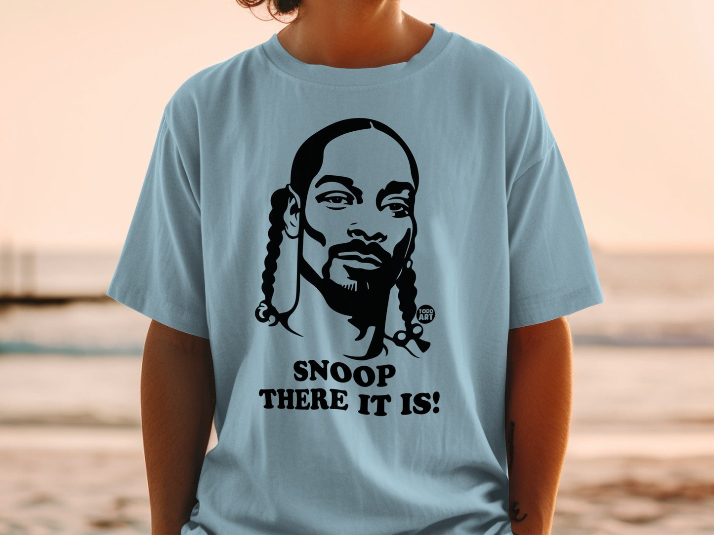 Snoop Dogg graphic on a light blue t-shirt with text "SNOOP THERE IT IS!".