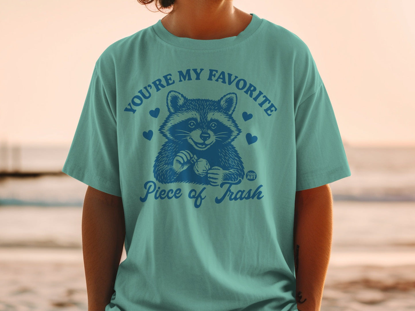 Teal t-shirt with a raccoon and "You're my favorite piece of trash" text.