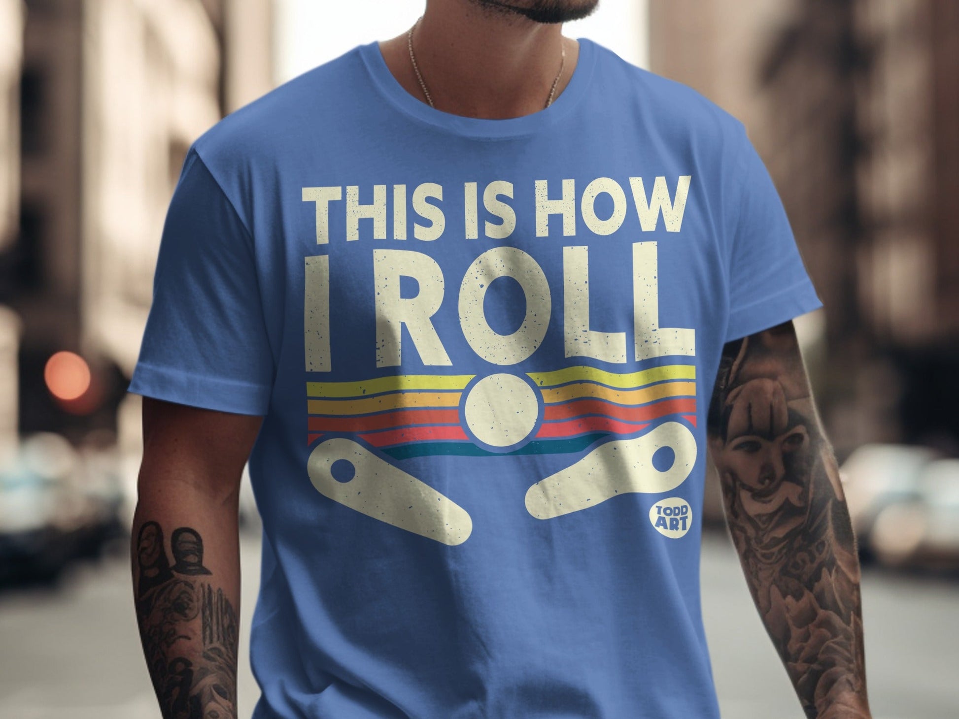 Blue t-shirt with "THIS IS HOW I ROLL" text and pinball graphic.