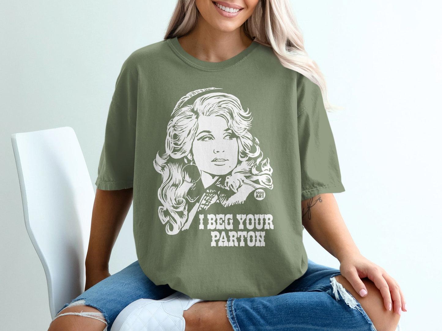 T-shirt featuring Dolly Parton graphic and "I Beg Your Parton" text.