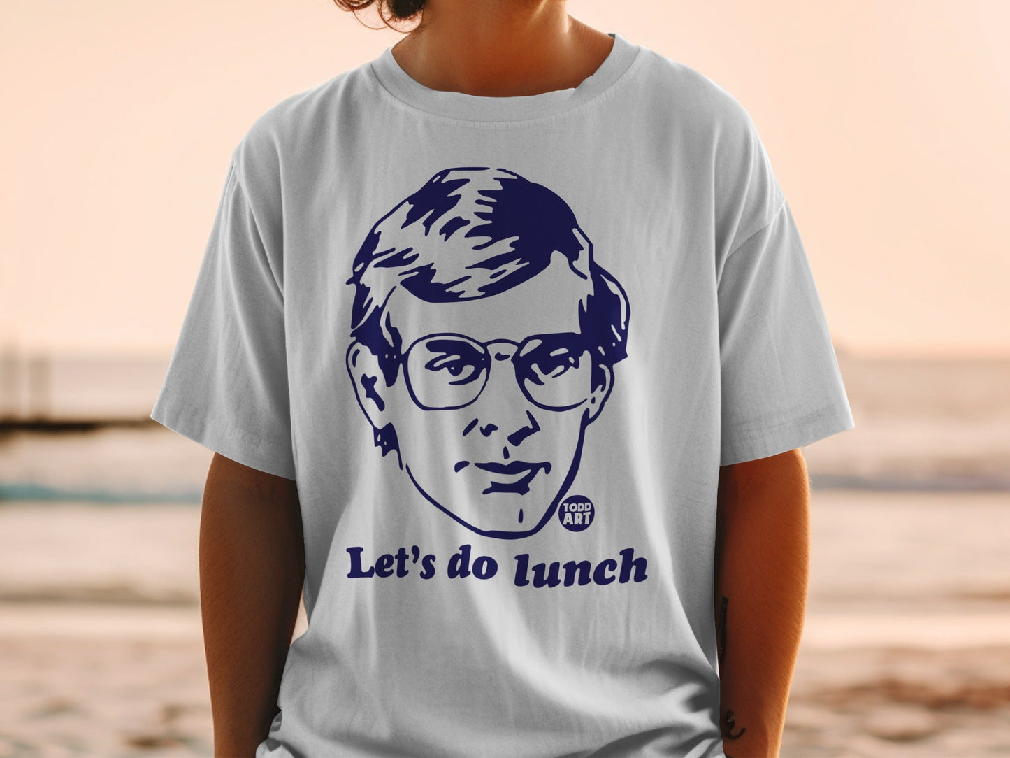 White t-shirt with navy blue graphic of a man's face and "Let's do lunch".