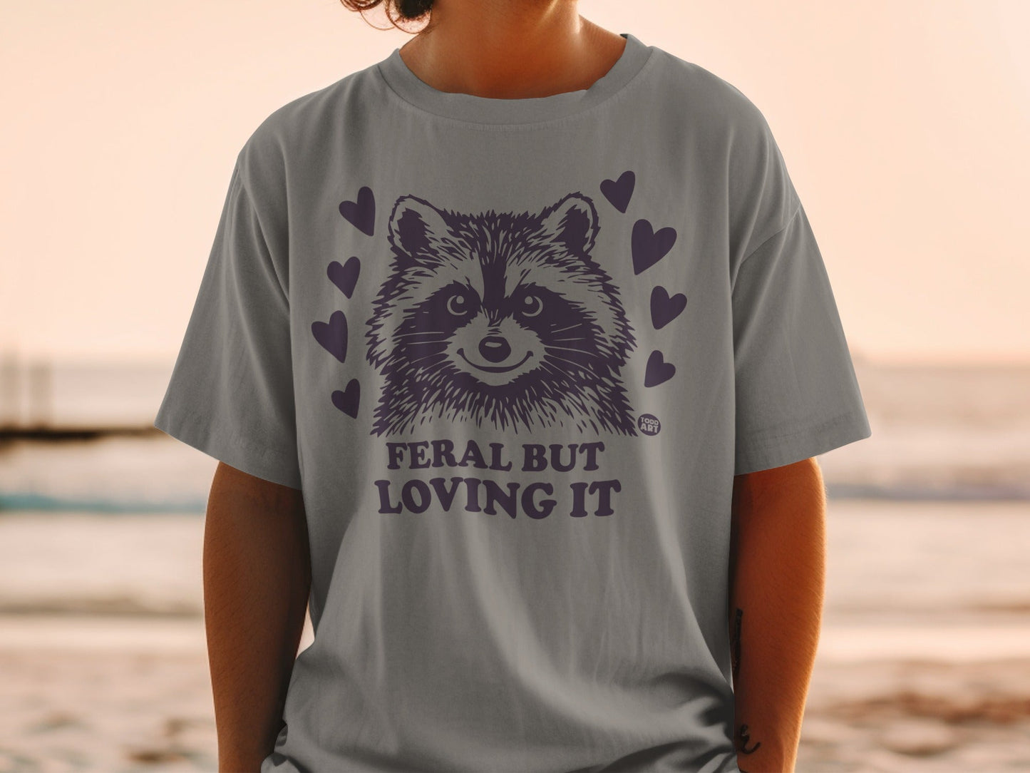 Grey t-shirt with raccoon graphic and "Feral But Loving It" text.