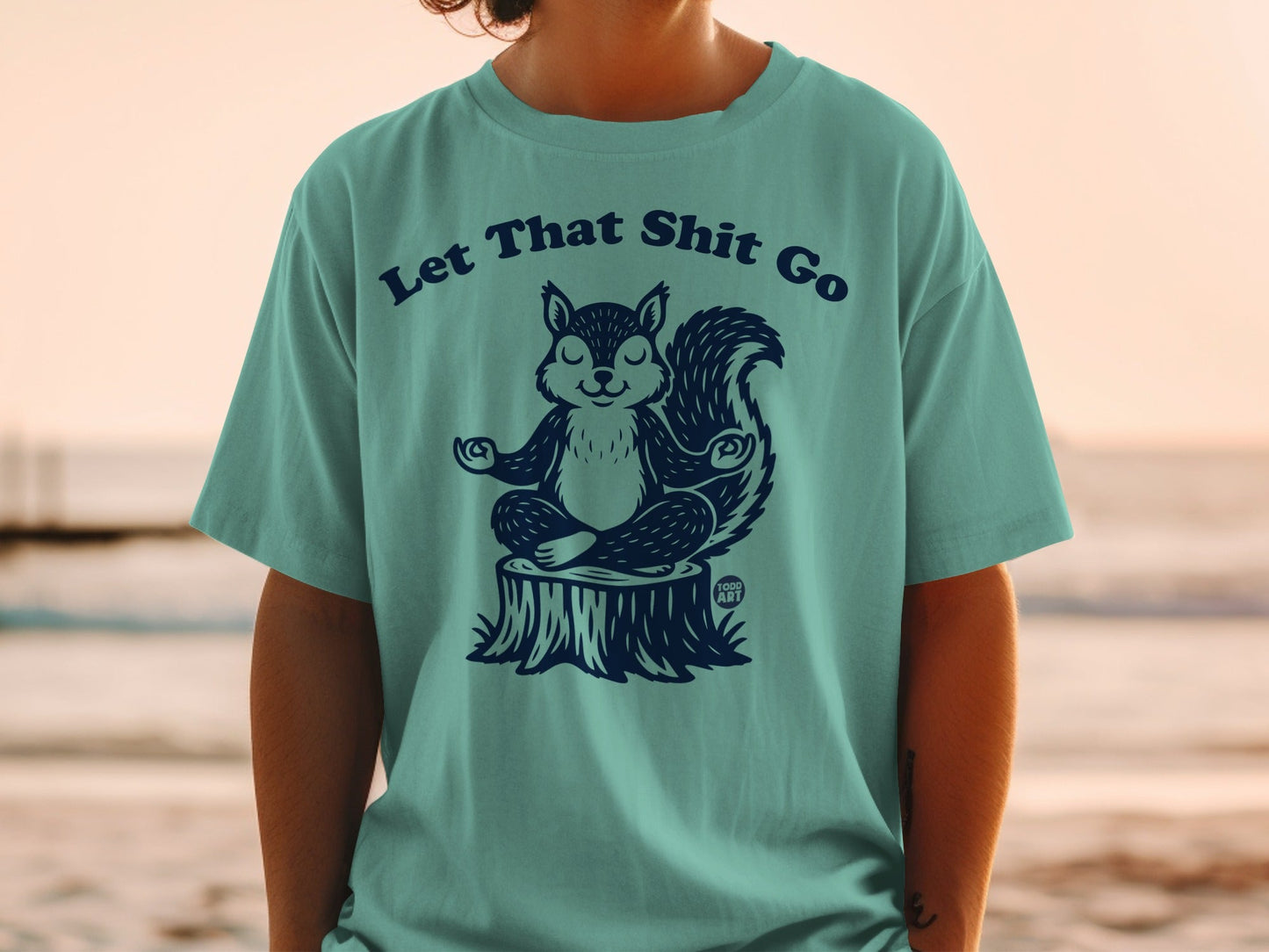 T-shirt with a meditating squirrel on a stump and the text "Let That Shit Go."