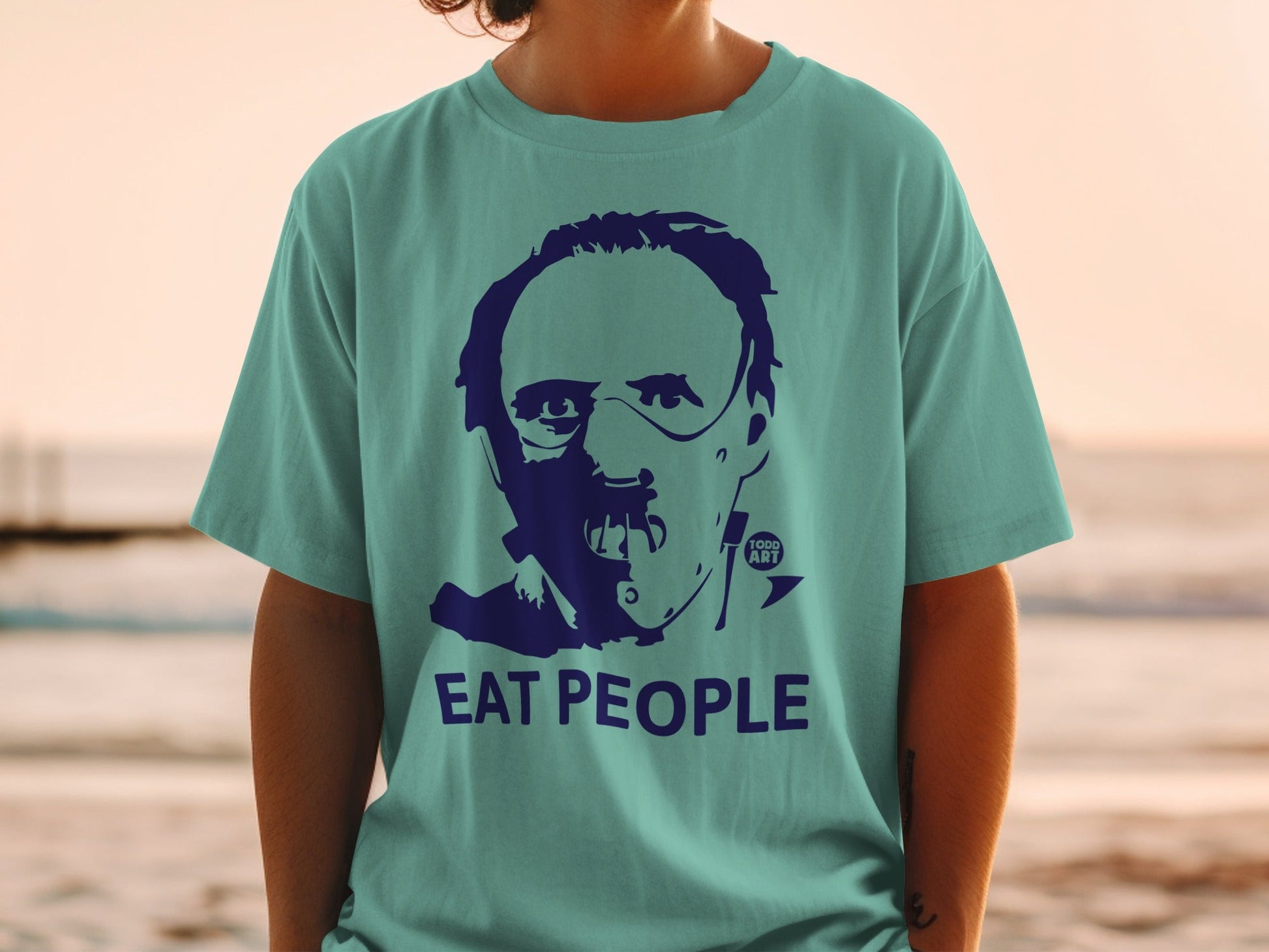 Teal t-shirt with a dark blue graphic of a man's face and text "EAT PEOPLE".