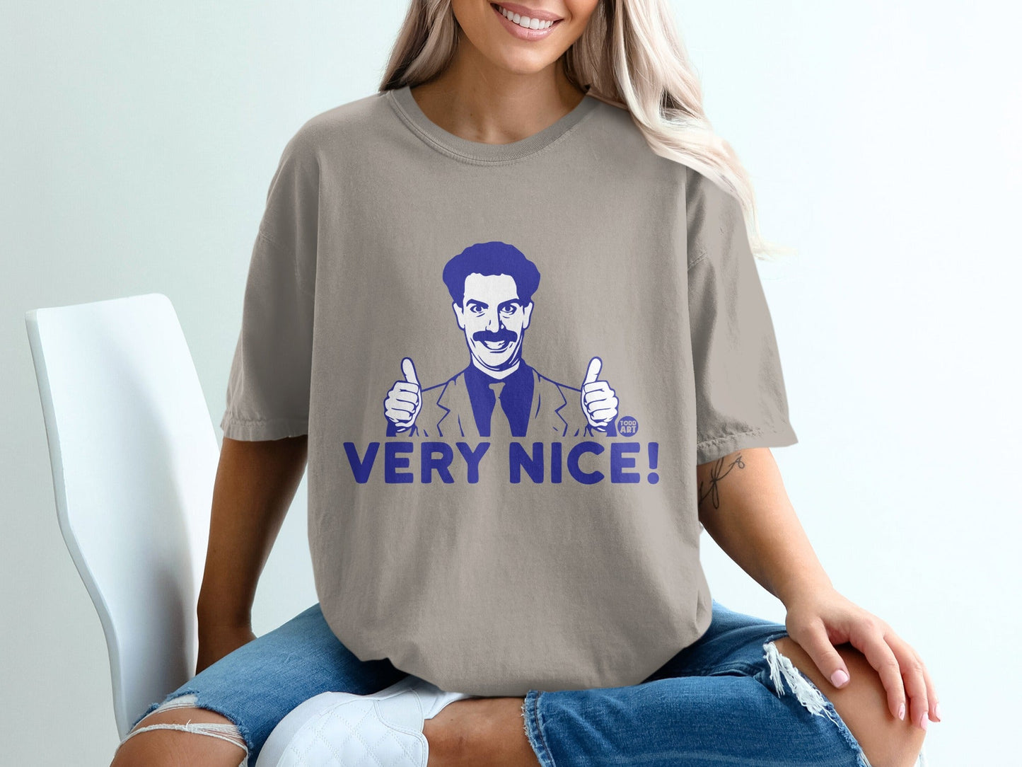 Tan t-shirt with blue "VERY NICE!" text and cartoon drawing of Borat giving thumbs up.