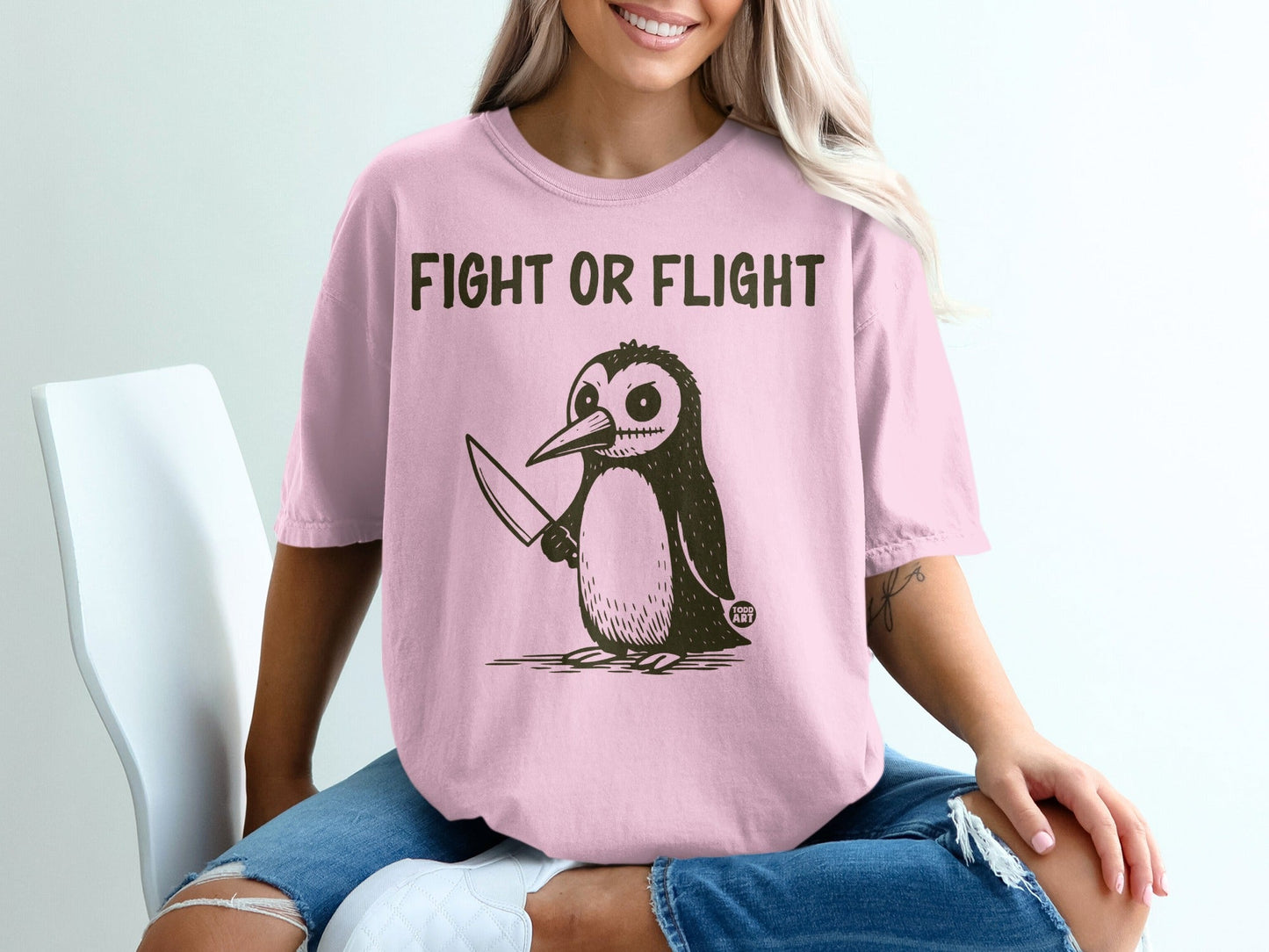Pink t-shirt with a cartoon penguin holding a knife and the text "FIGHT OR FLIGHT".