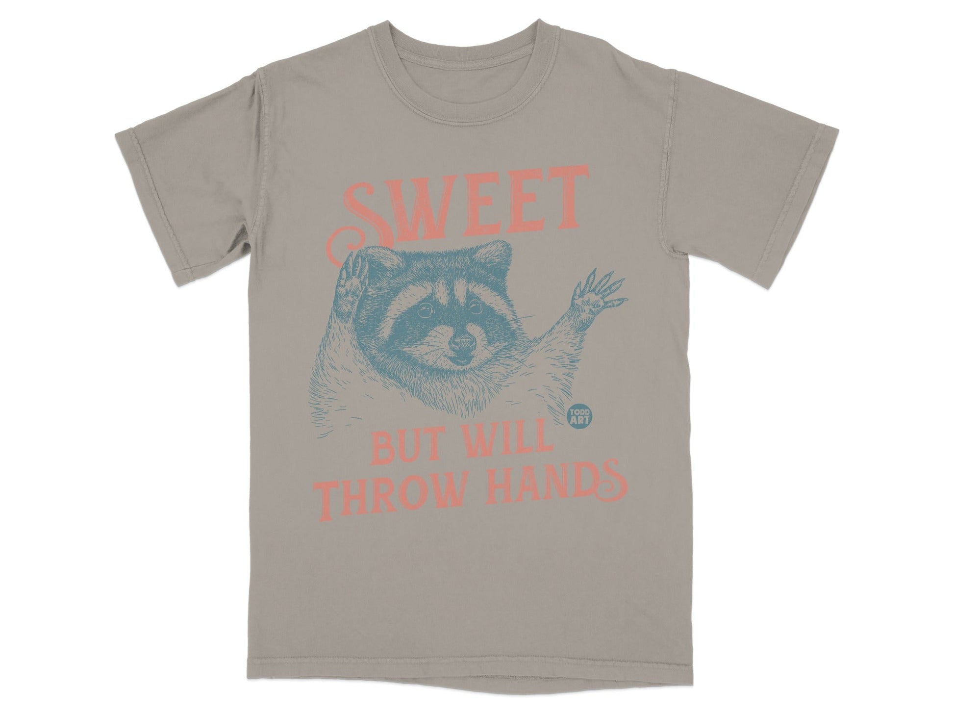 T-shirt with raccoon illustration and text "SWEET BUT WILL THROW HANDS".