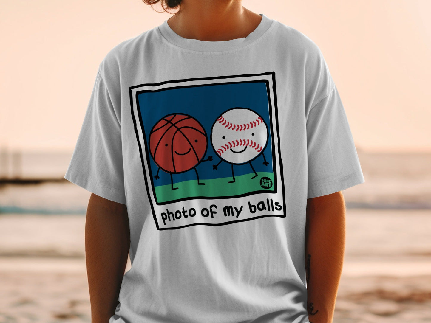 Cartoon basketball and baseball characters holding hands on a white t-shirt.